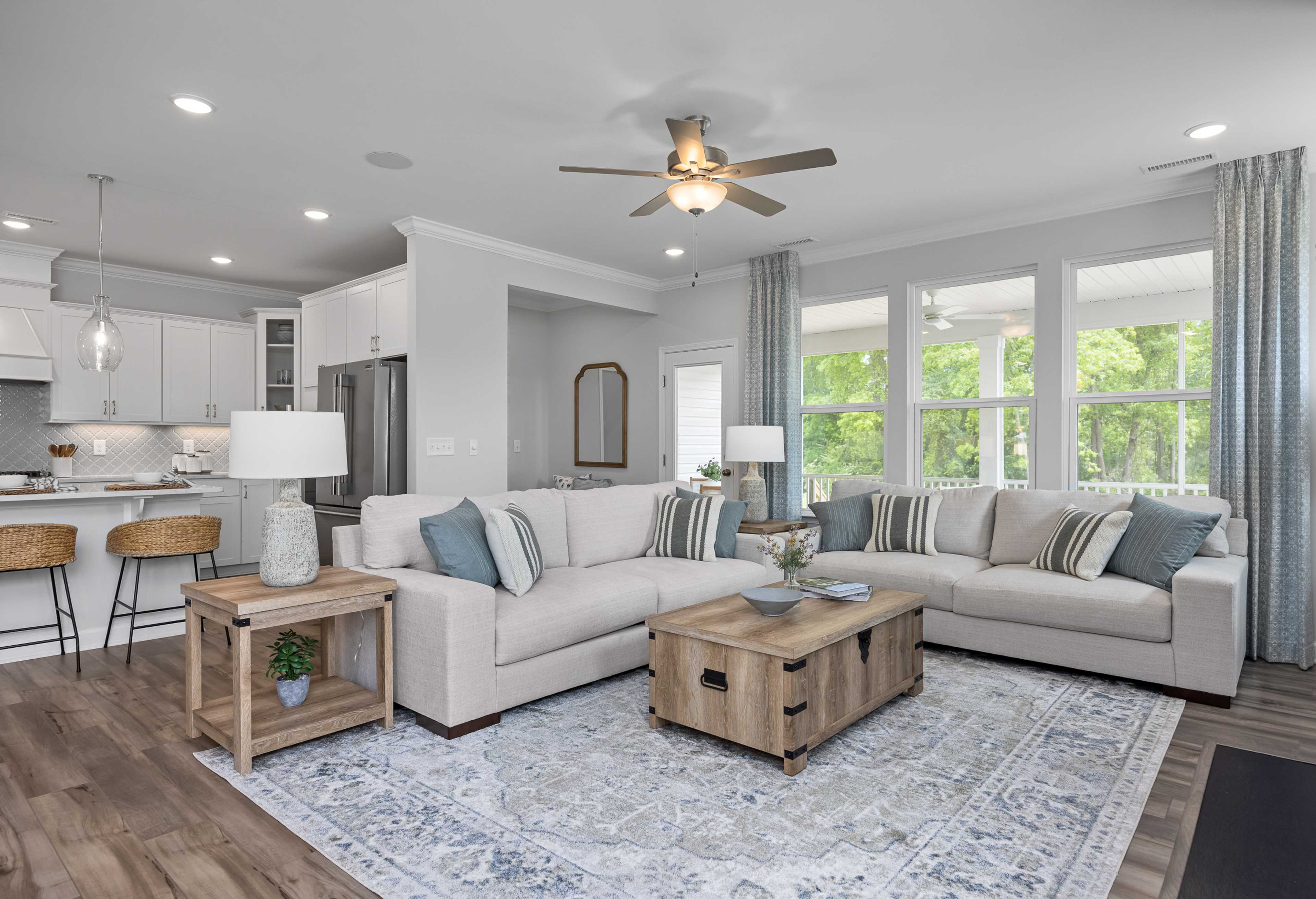 Spacious open-concept living room in The Magnolia A, Davidson Homes, Mooresville NC, with beige sectional sofa, wooden coffee table, and adjacent kitchen island