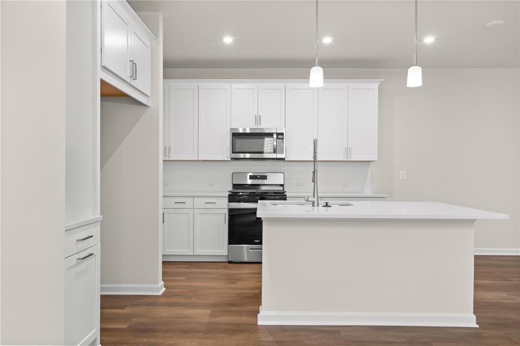 Bright modern kitchen with white shaker cabinets, stainless steel appliances, and large quartz island in Davidson Homes The Marion B, Kennesaw, GA