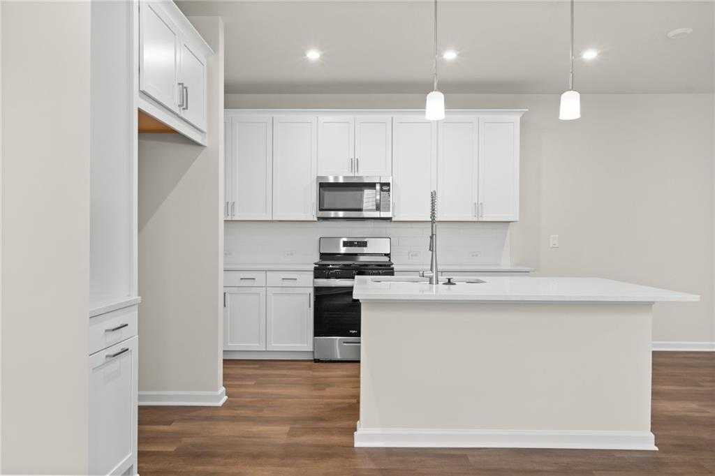 Bright modern kitchen with white shaker cabinets, stainless steel appliances, and large quartz island in Davidson Homes The Marion B, Kennesaw, GA
