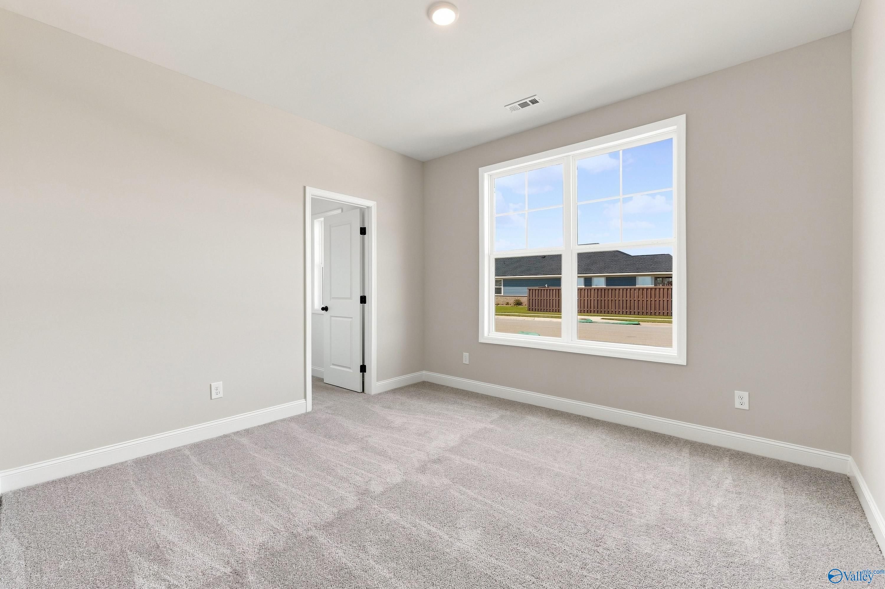 Bright carpeted bedroom with large window at Davidson Homes Montgomery D plan in Anderson Farm, Athens, Alabama