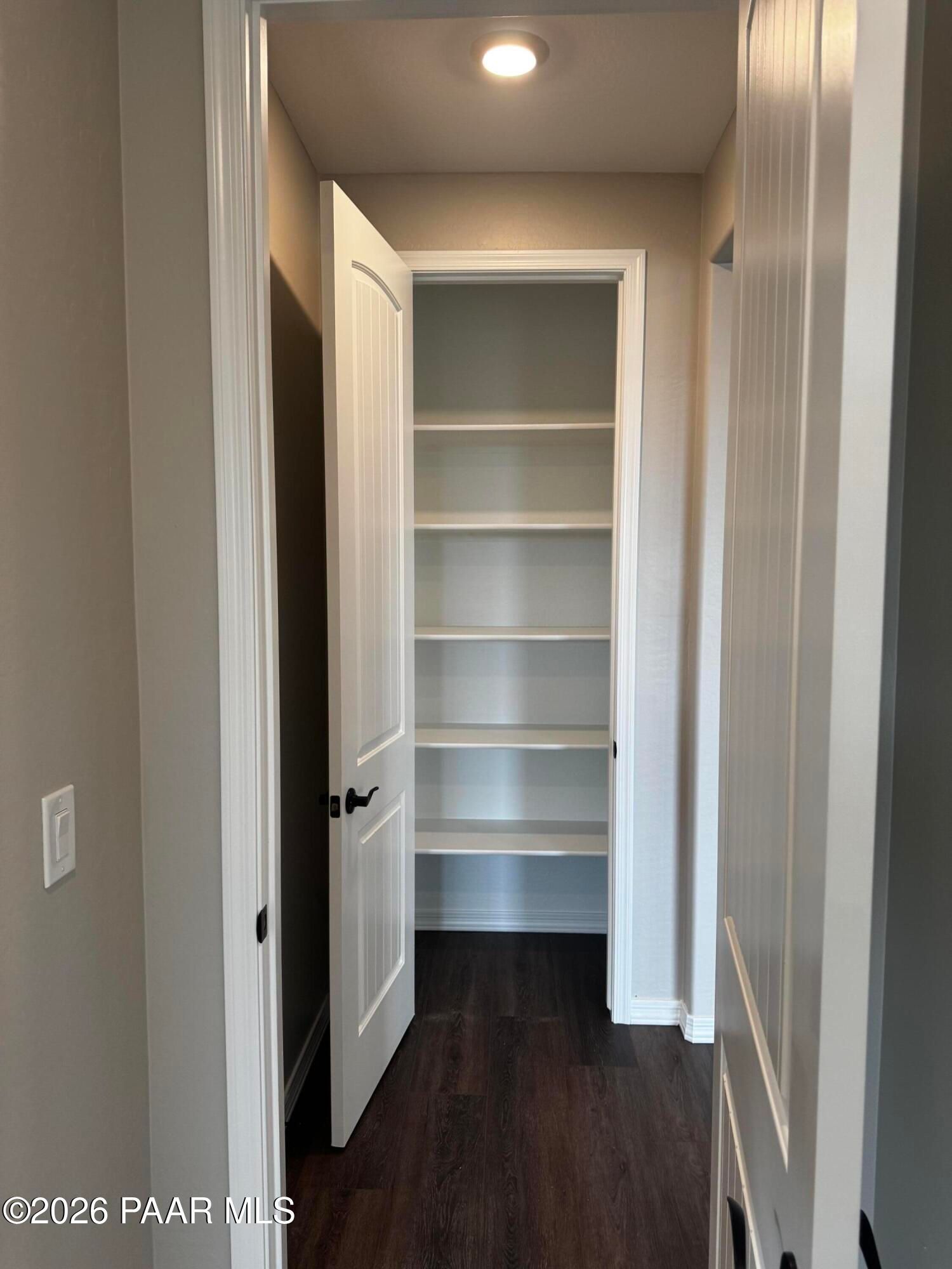 Spacious walk-in closet with white shelves and open doors on hardwood floors in Davidson Homes The Durango II B, Prescott, Arizona