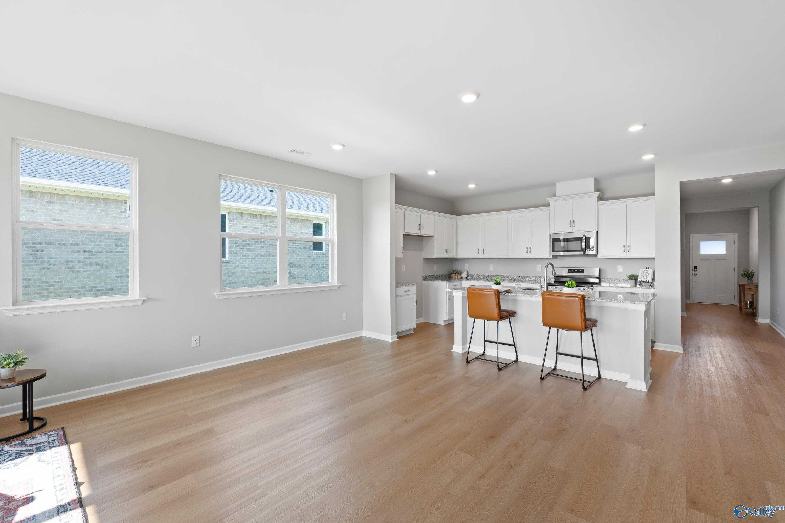 Modern open-concept kitchen with white cabinets, stainless appliances, bar island, and hardwood floors in Davidson Homes The Aurora, Fayetteville TN