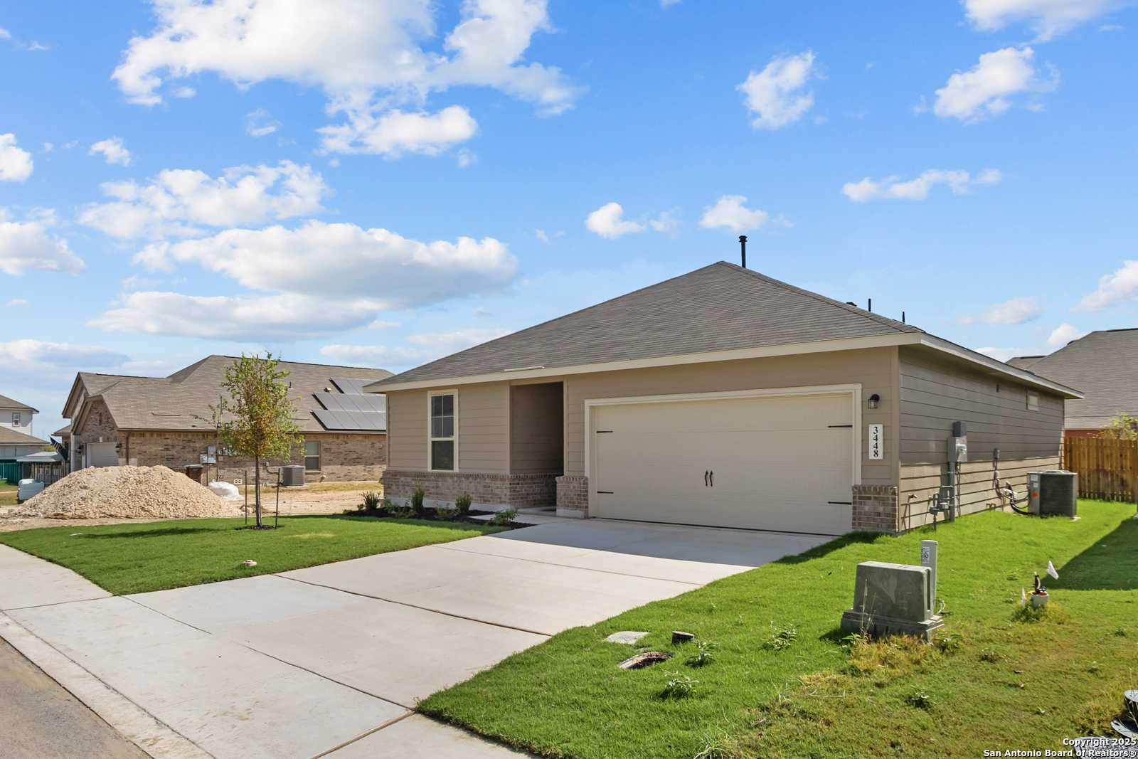 Modern tan single-story 3-bedroom home with 2-car garage and lush lawn in Horizon Pointe, Converse, Texas by Davidson Homes The Asheville E