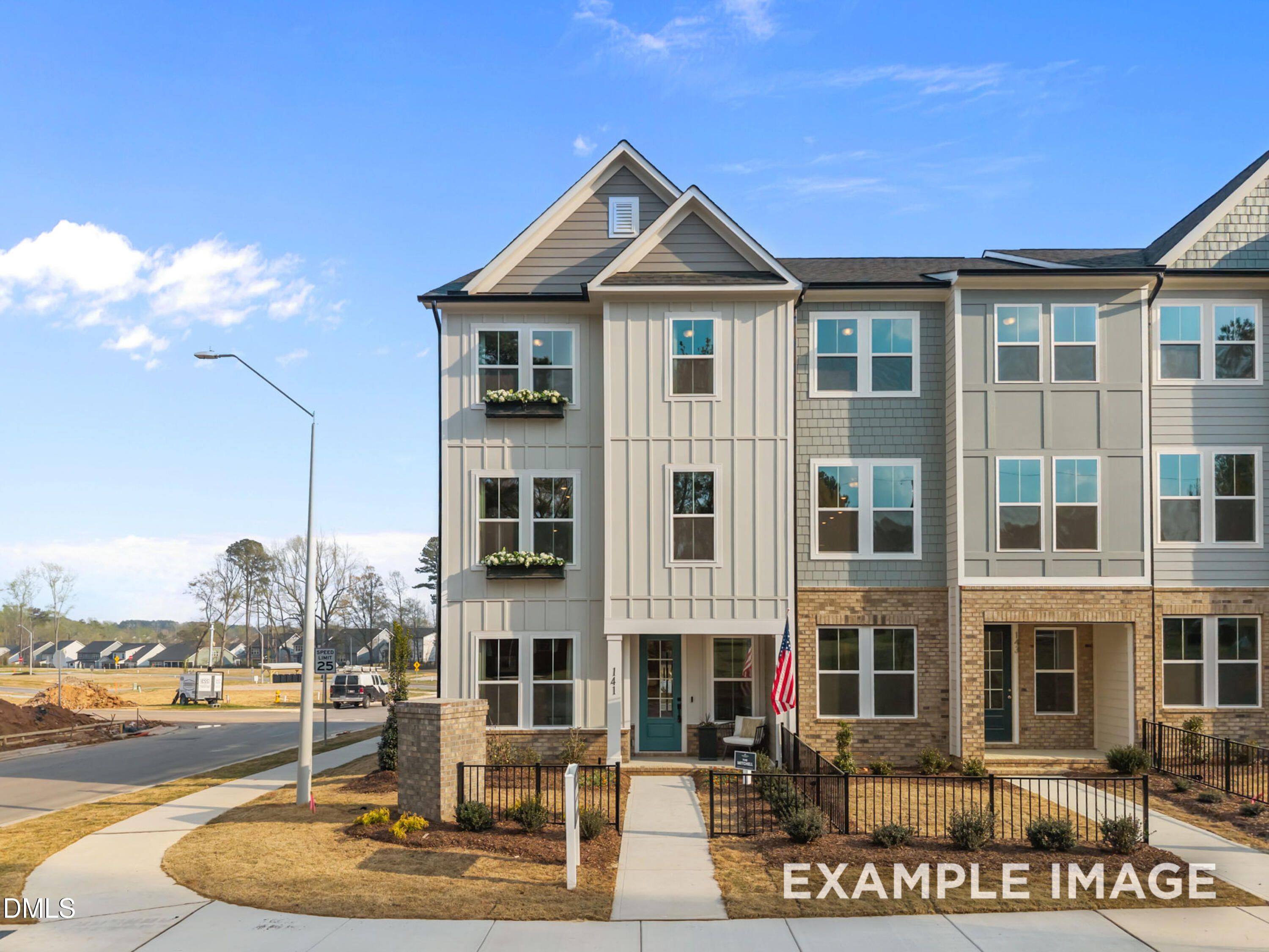 Modern 3-story townhome exterior with teal door, flower boxes, and American flag in Camden Park, Knightdale, NC - Davidson Homes Mitchell plan