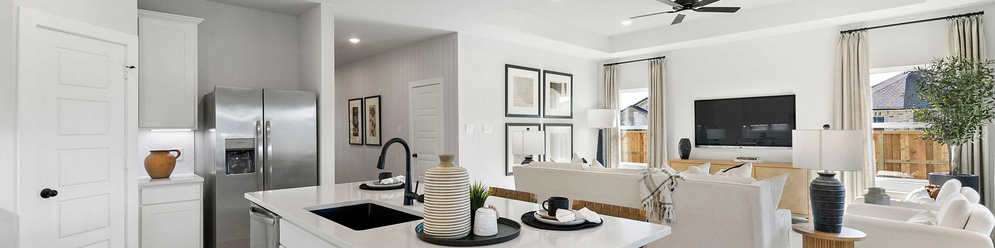 Open-concept kitchen and living room in Sundance Cove Crosby Texas with white island, hardwood floors, ceiling fan and modern white seating