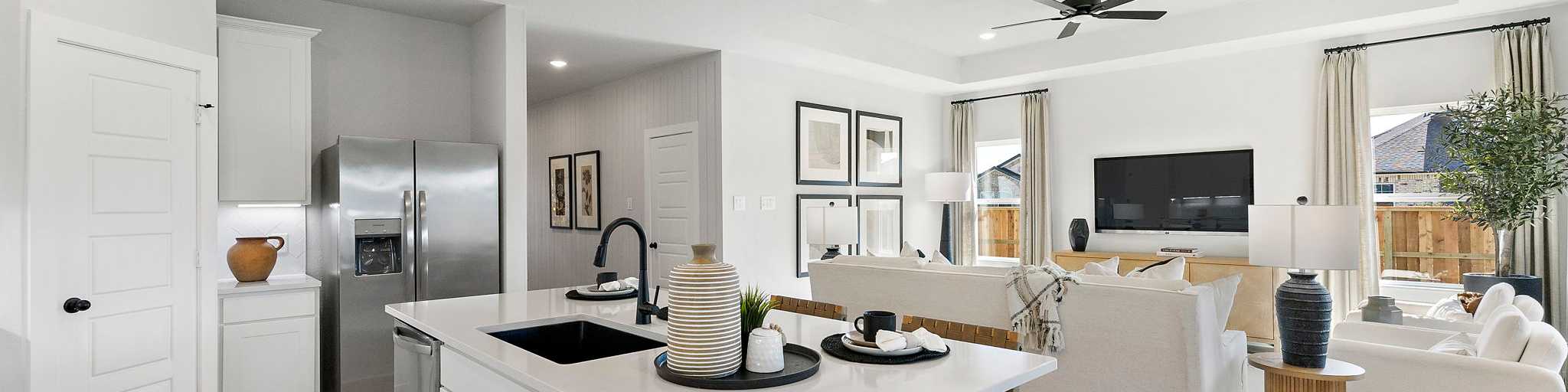 Open-concept kitchen and living room in Sundance Cove Crosby Texas with white island, hardwood floors, ceiling fan and modern white seating