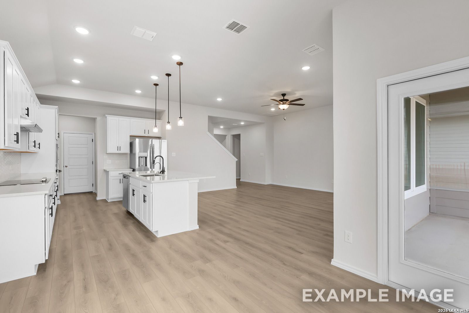 Open-concept kitchen with white cabinets and island in The Sequoia C floor plan at Royal Crest, San Antonio.