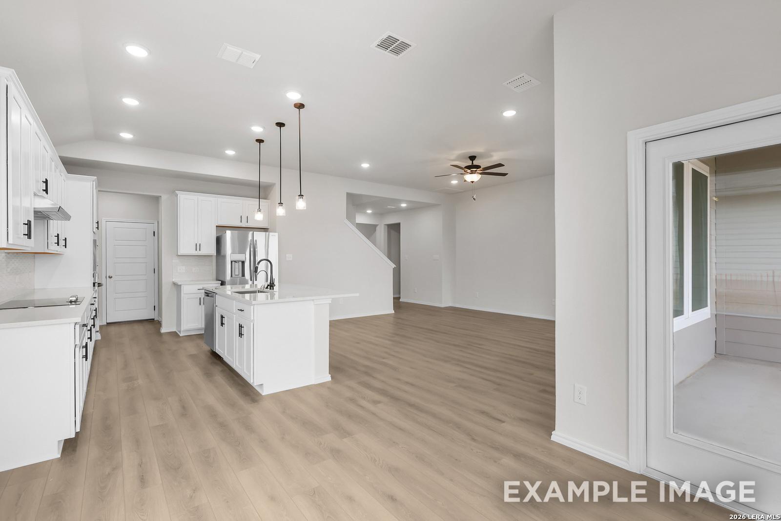 Open-concept kitchen with white cabinets and island in The Sequoia C floor plan at Royal Crest, San Antonio.