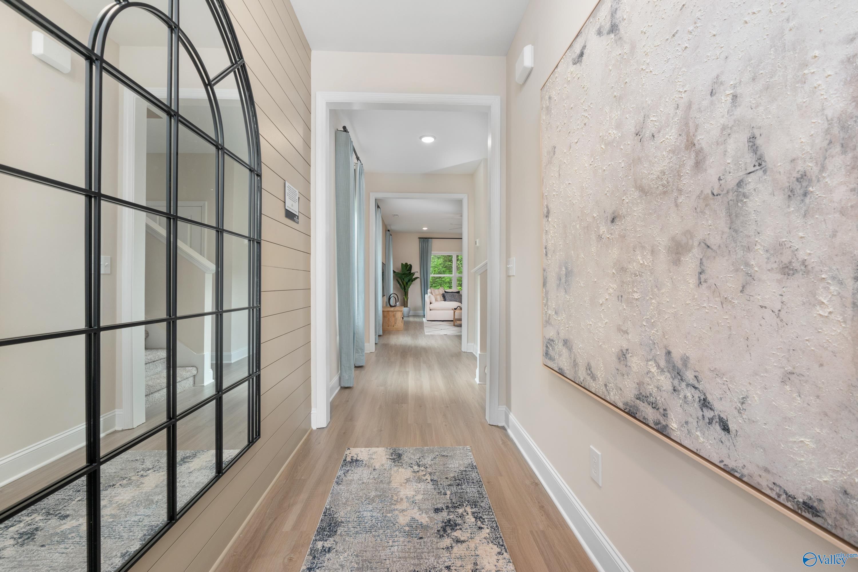 Elegant entry hallway with arched black mirror, abstract art, wood floors in Davidson Homes The Camden, Huntsville AL