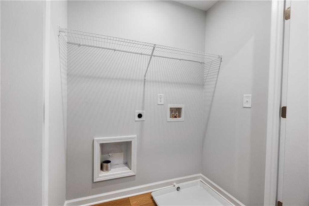 Functional laundry room featuring utility sink, wire shelving, and washer-dryer hookups in The Durant A, Stegall Village, Emerson, Georgia