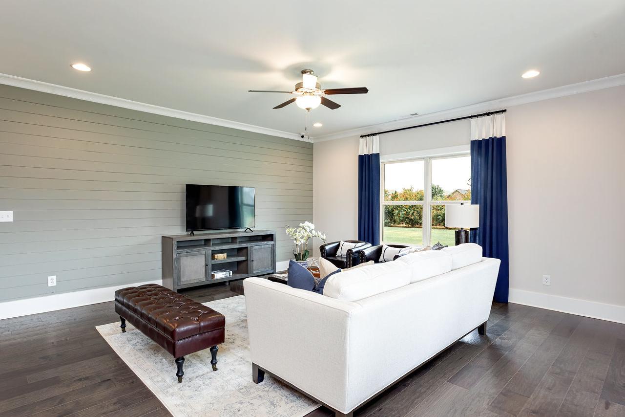 Spacious living room at Williams Pointe in Huntsville AL featuring white sectional sofa, gray shiplap walls, hardwood floors, and navy curtained windows