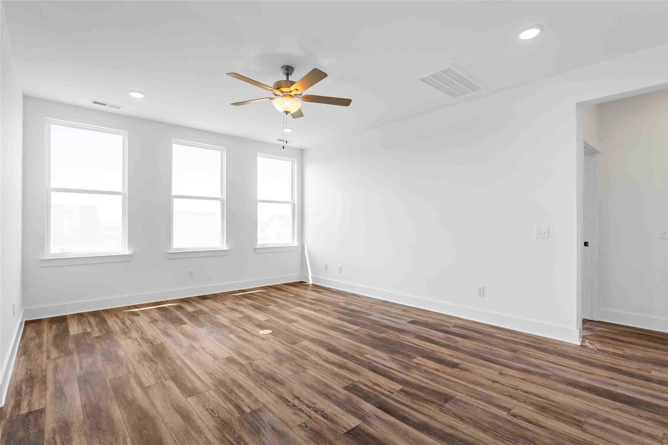 Bright, spacious living area with wood-look flooring and ceiling fan in Davidson Homes The Ash O floor plan in Heartland, TX