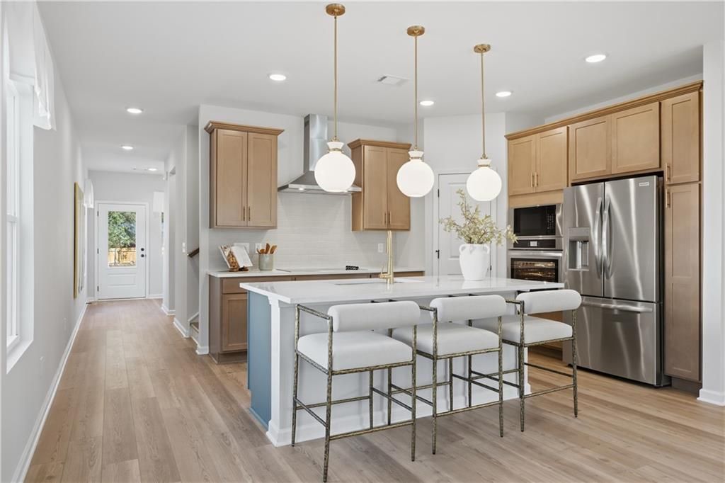 Kitchen island with white quartz countertop, brass pendant lights, and bar stools in Davidson Homes The Sinclair B, Cartersville, GA