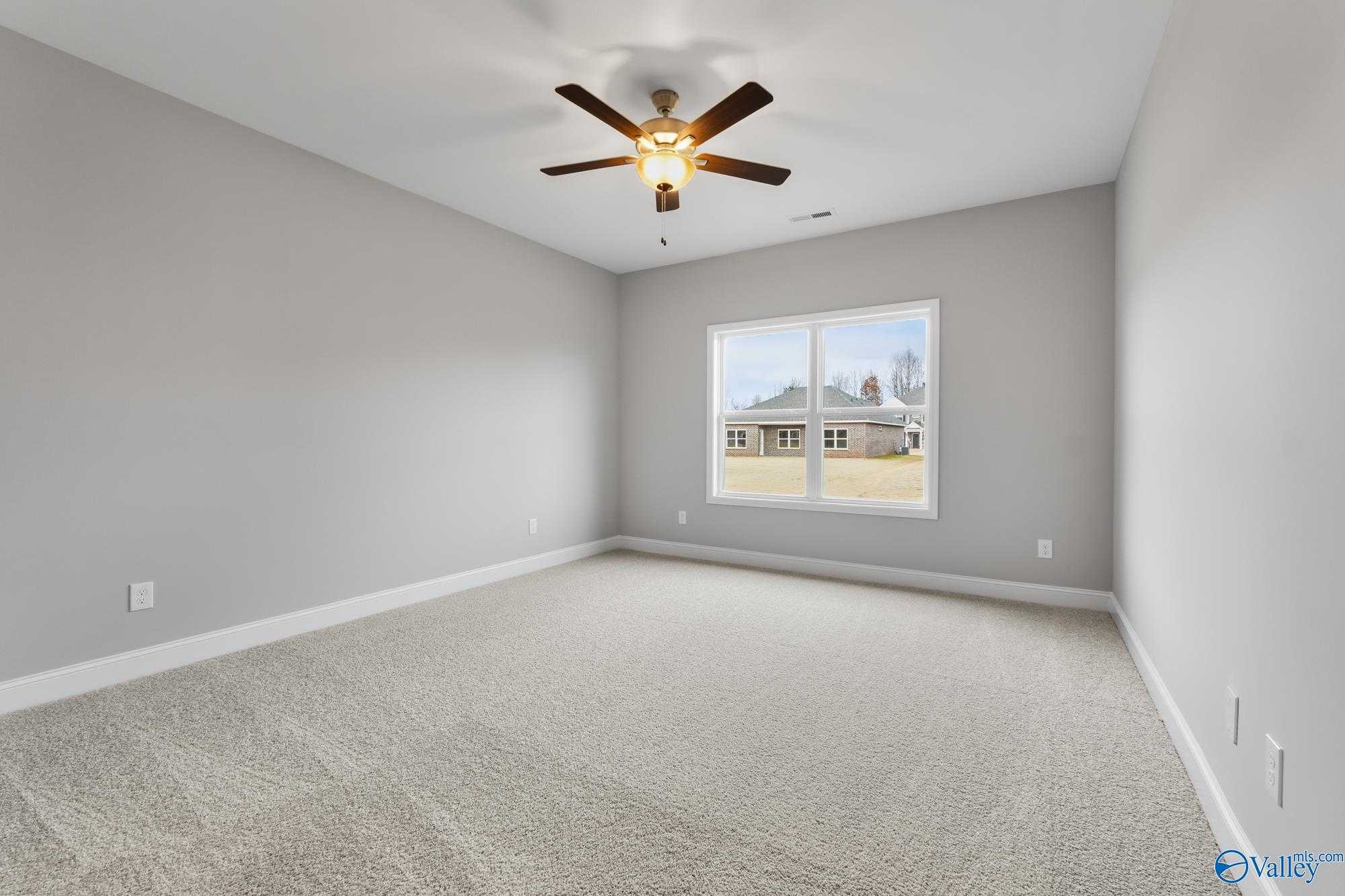 Spacious secondary bedroom with gray walls, beige carpet, ceiling fan, and window view in Davidson Homes The Daphne D, Athens AL