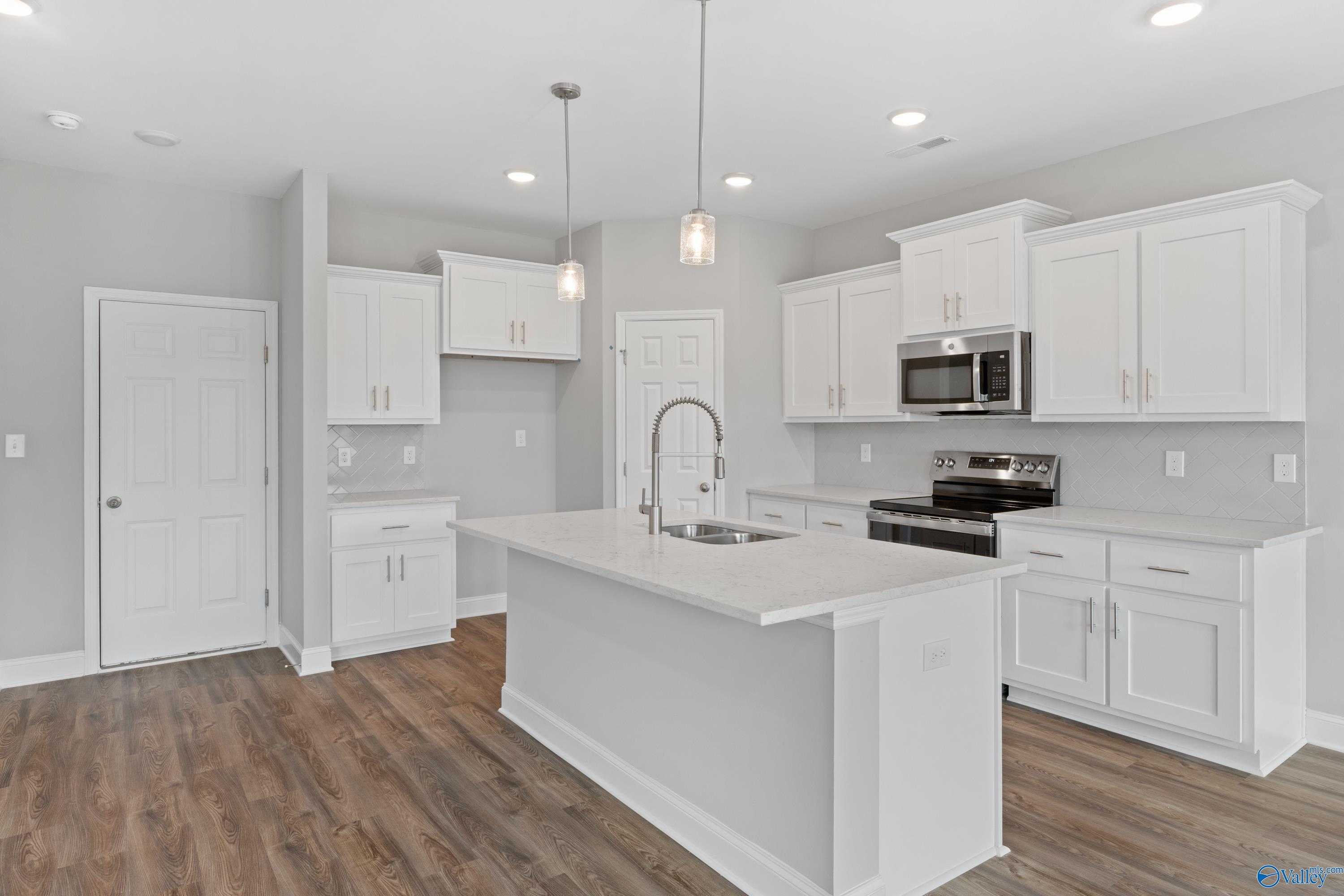 Modern white kitchen with shaker cabinets, stainless appliances, quartz island sink in Davidson Homes The Aiken, Meridianville AL