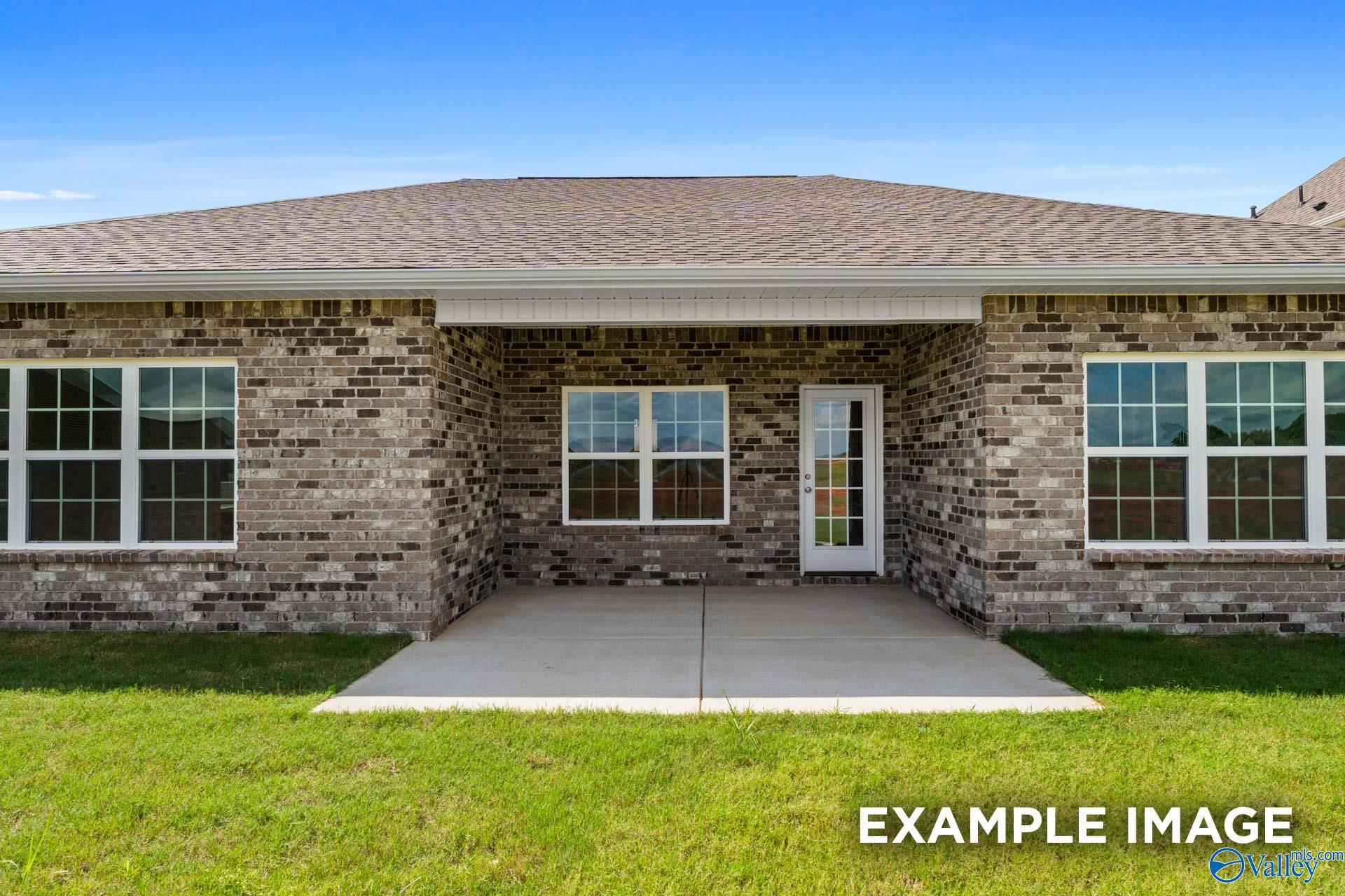 Brick home rear with covered patio, double windows, glass door, lush lawn in Davidson Homes The Montgomery, Hartselle AL