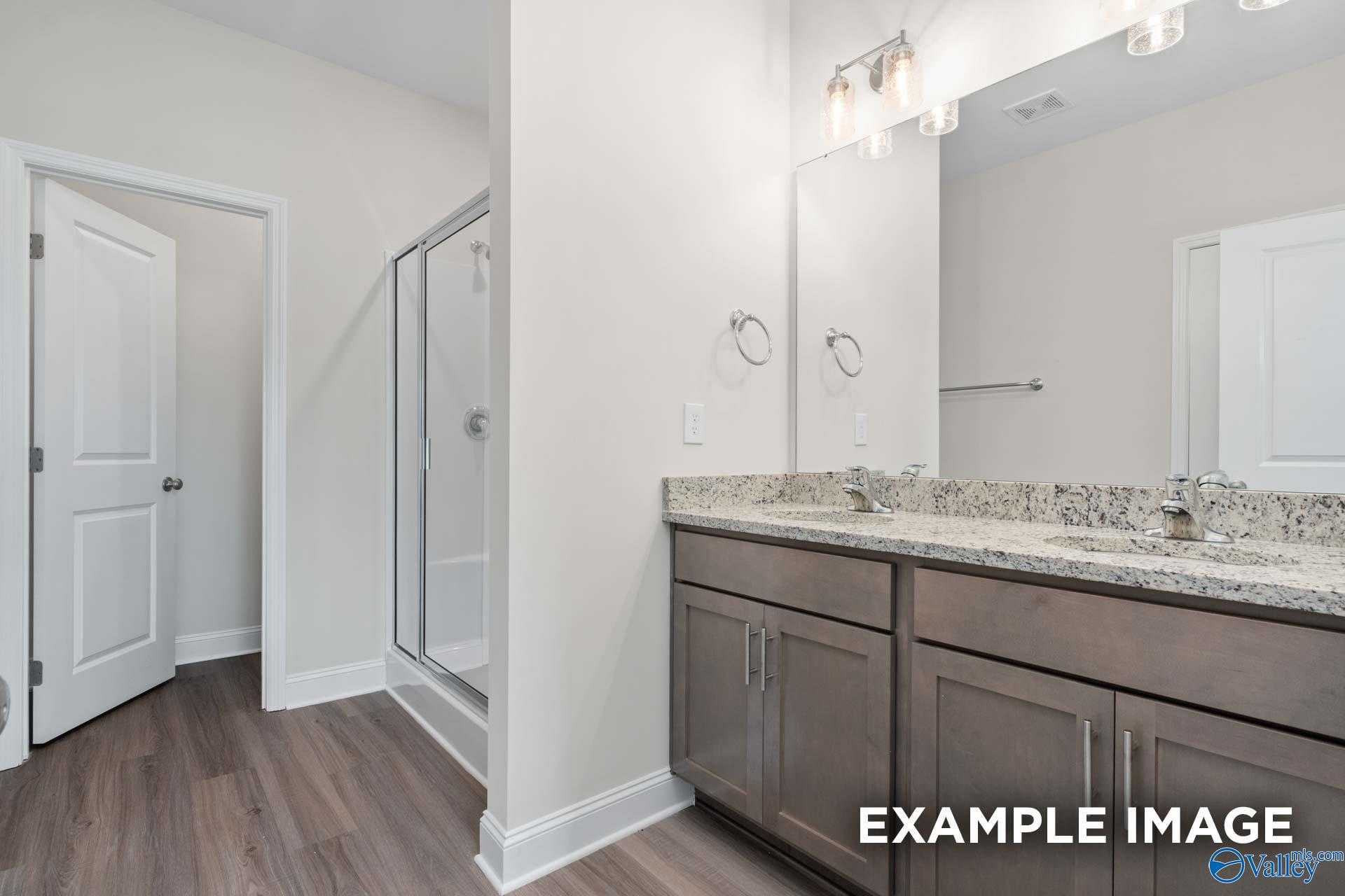 Modern master bathroom featuring double granite vanity, walk-in shower, and ample storage in Davidson Homes The Daphne D, Arab, Alabama
