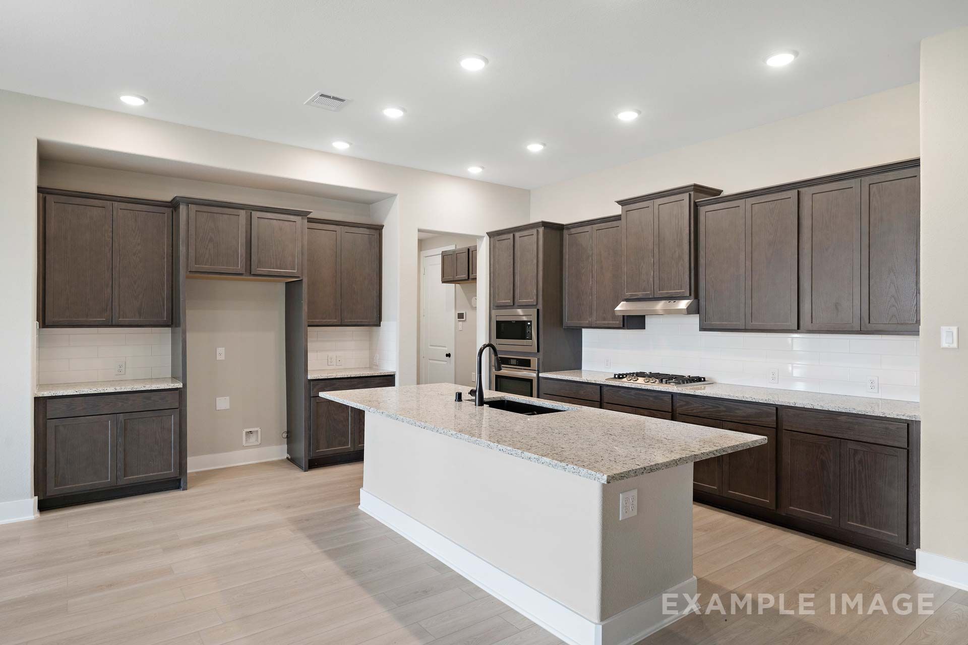 Gourmet kitchen in The Elizabeth by Davidson Homes featuring granite island, dark cabinetry, and subway tile backsplash