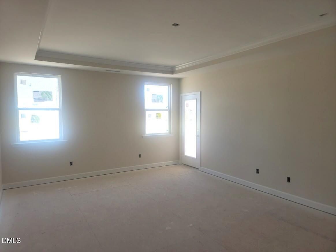 Bright empty living room with large windows, beige walls, and carpeted floor in Davidson Homes The Cypress B II, Angier, NC