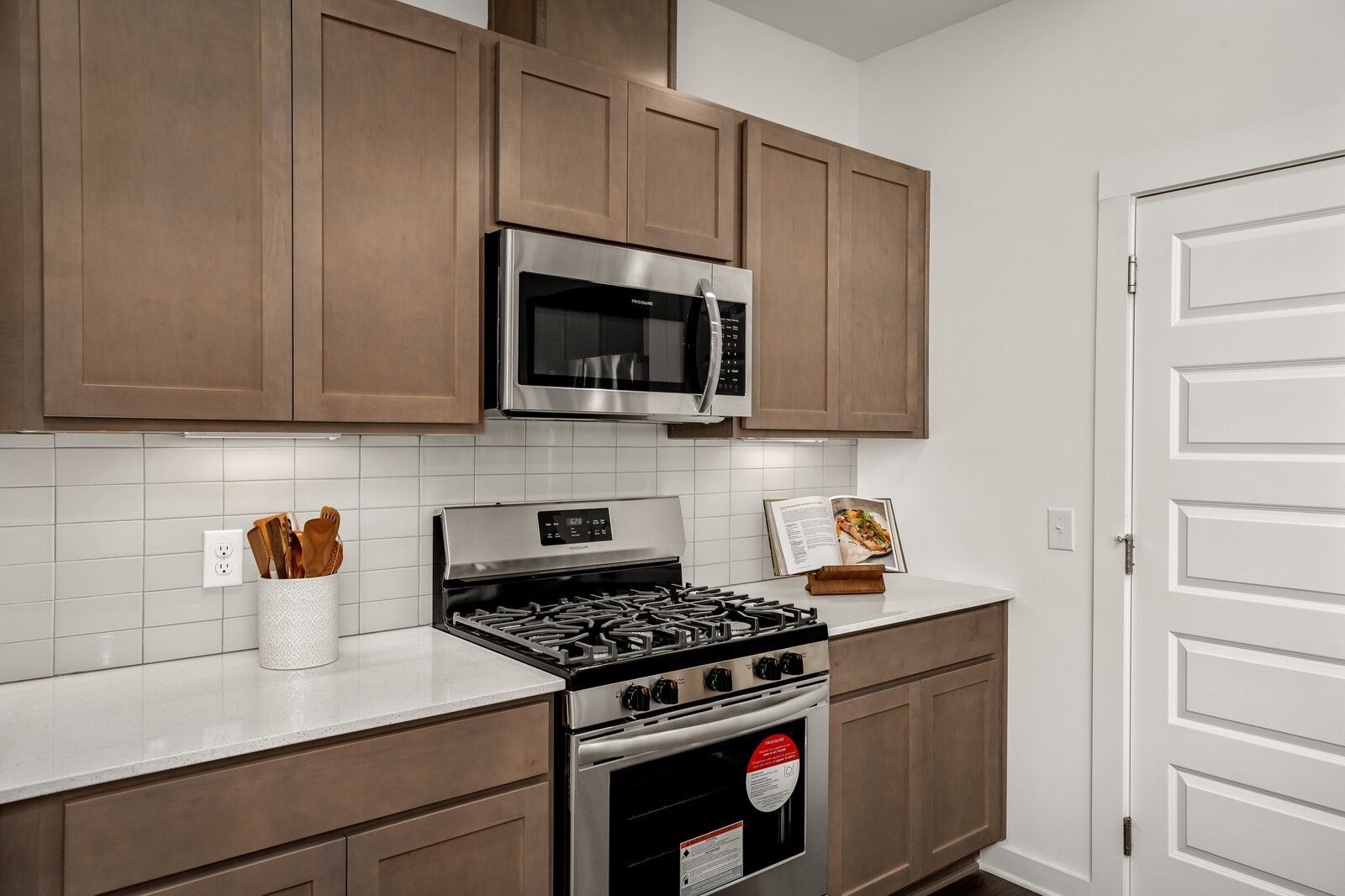 Modern kitchen featuring beige shaker cabinets, white quartz counters, subway tile backsplash, stainless steel Frigidaire appliances in Davidson Homes The Gordon C, White House TN