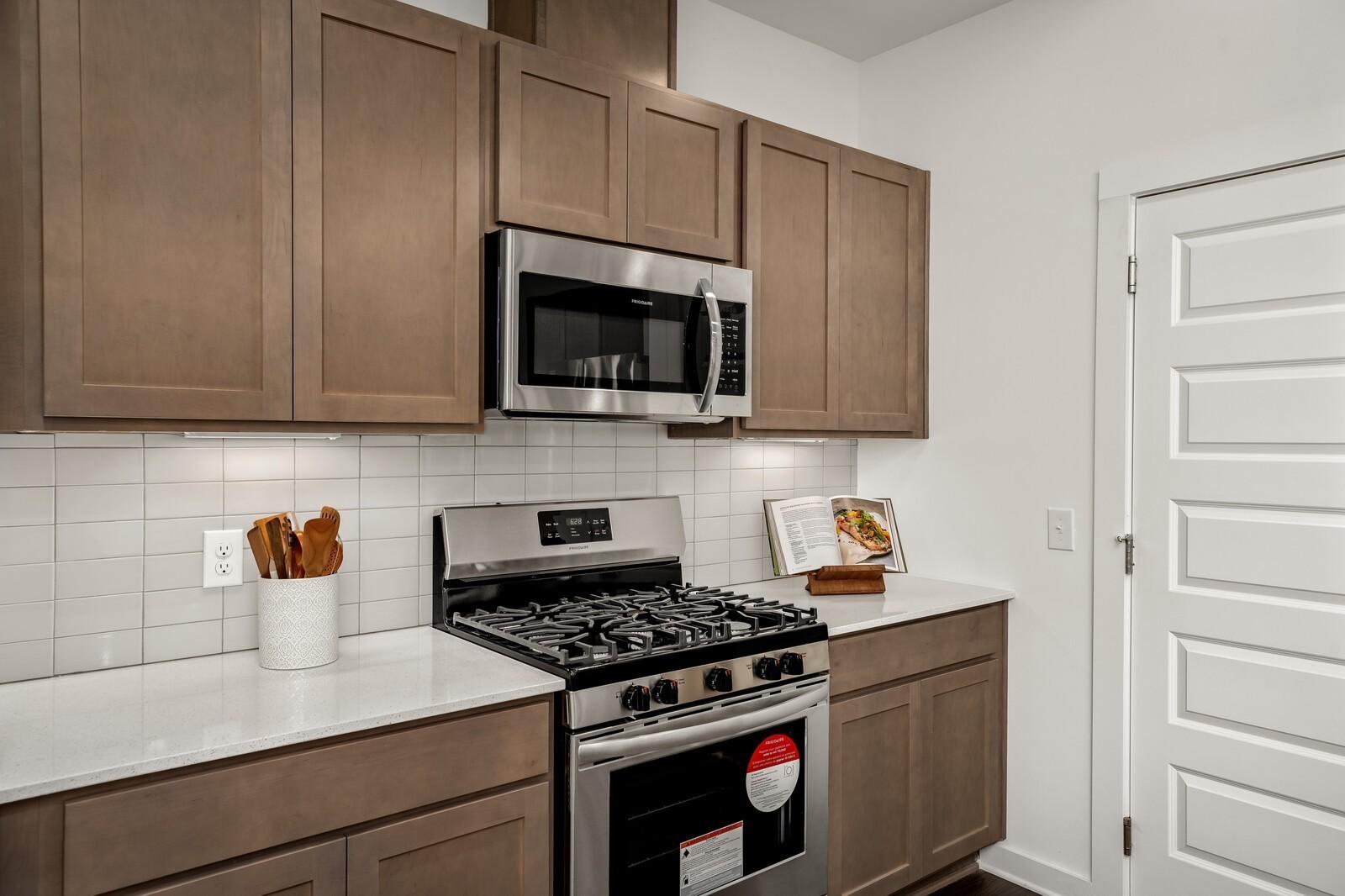 Modern kitchen featuring beige shaker cabinets, white quartz counters, subway tile backsplash, stainless steel Frigidaire appliances in Davidson Homes The Gordon C, White House TN