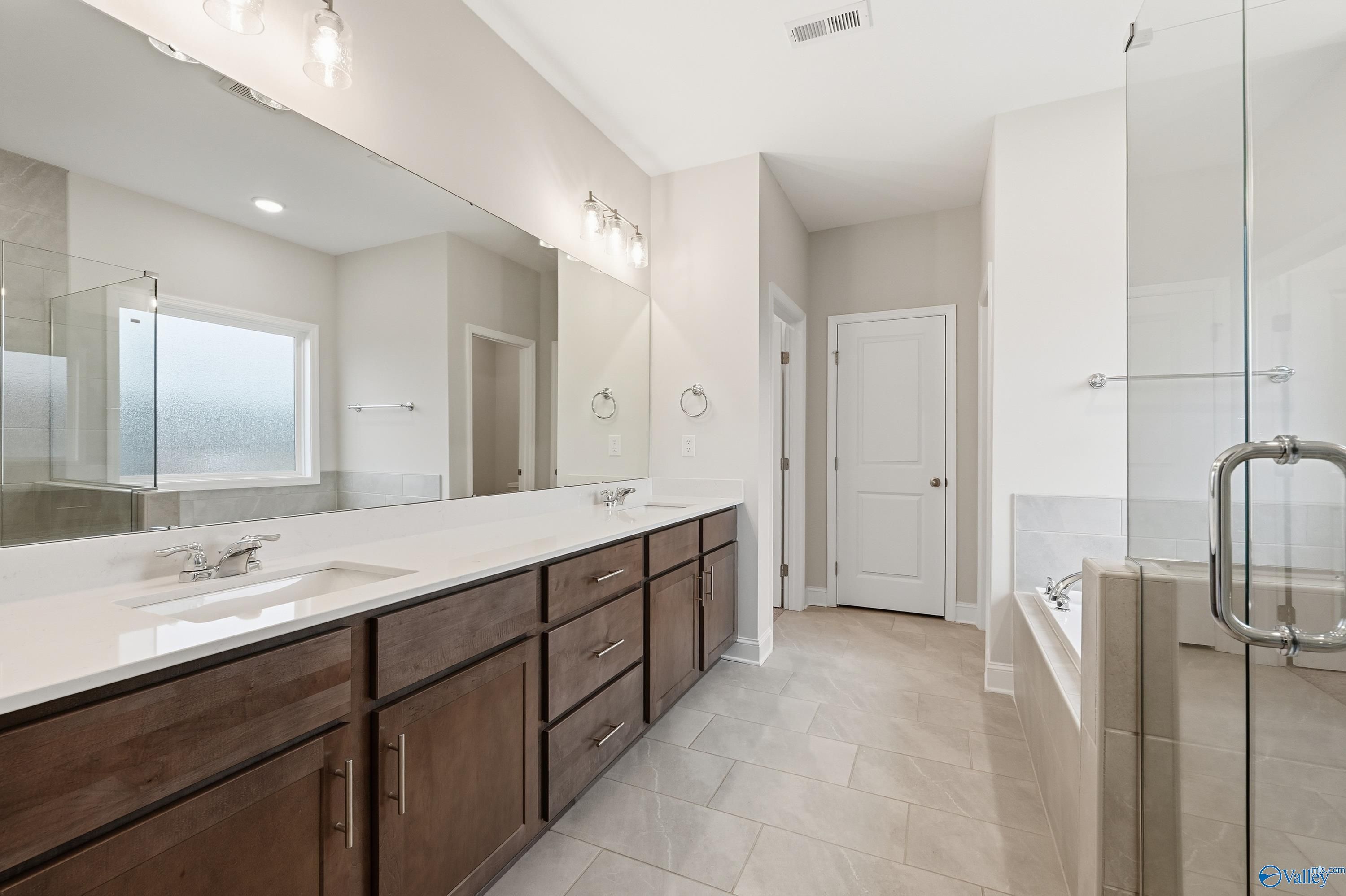 Elegant master bathroom with double vanity, freestanding tub, and glass shower in Davidson Homes The Kirkland, Decatur, Alabama