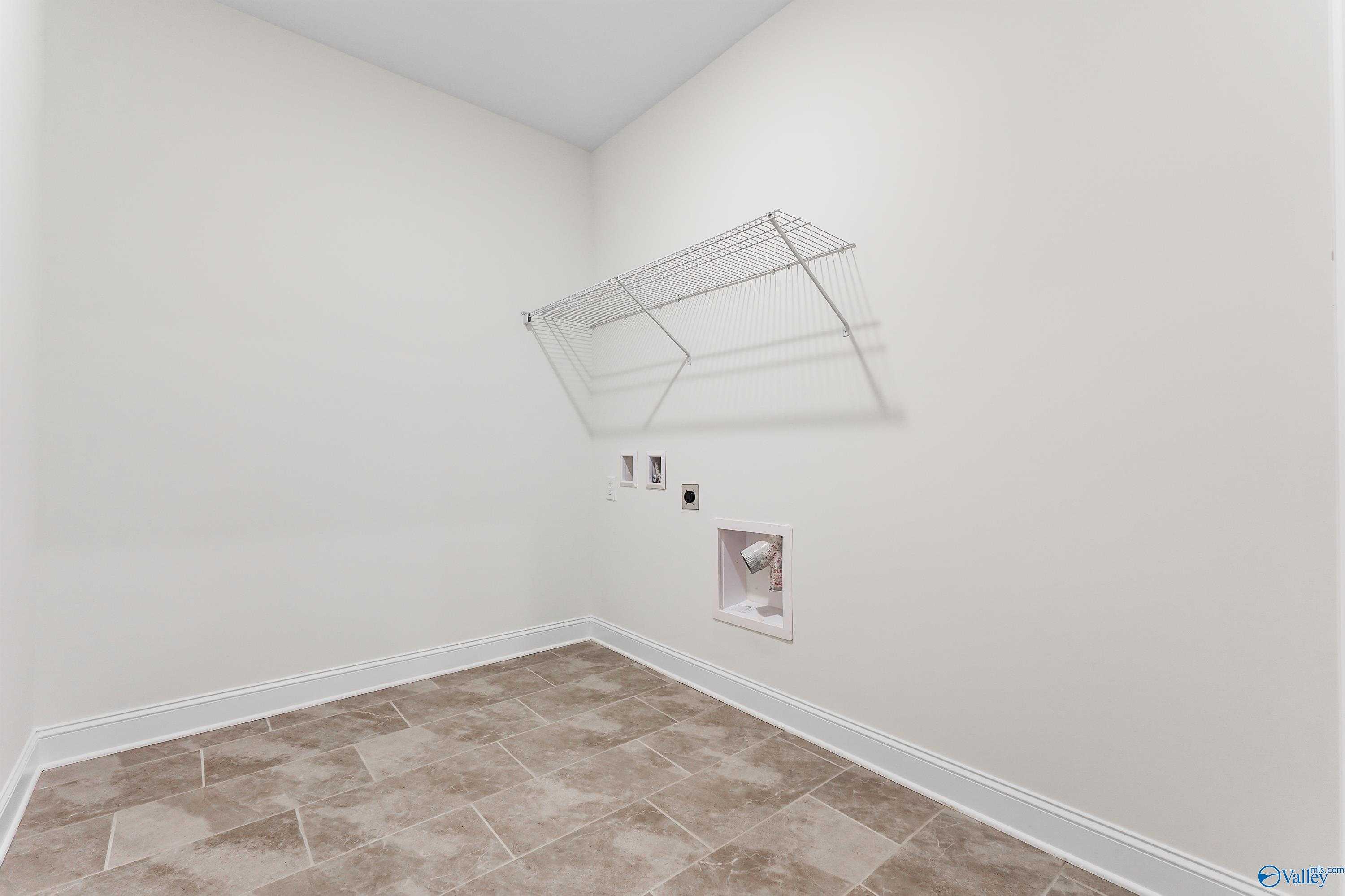 Spacious laundry room with wire shelving, washer dryer hookups, and beige tile floor in The Finleigh, Davidson Homes, Harvest AL