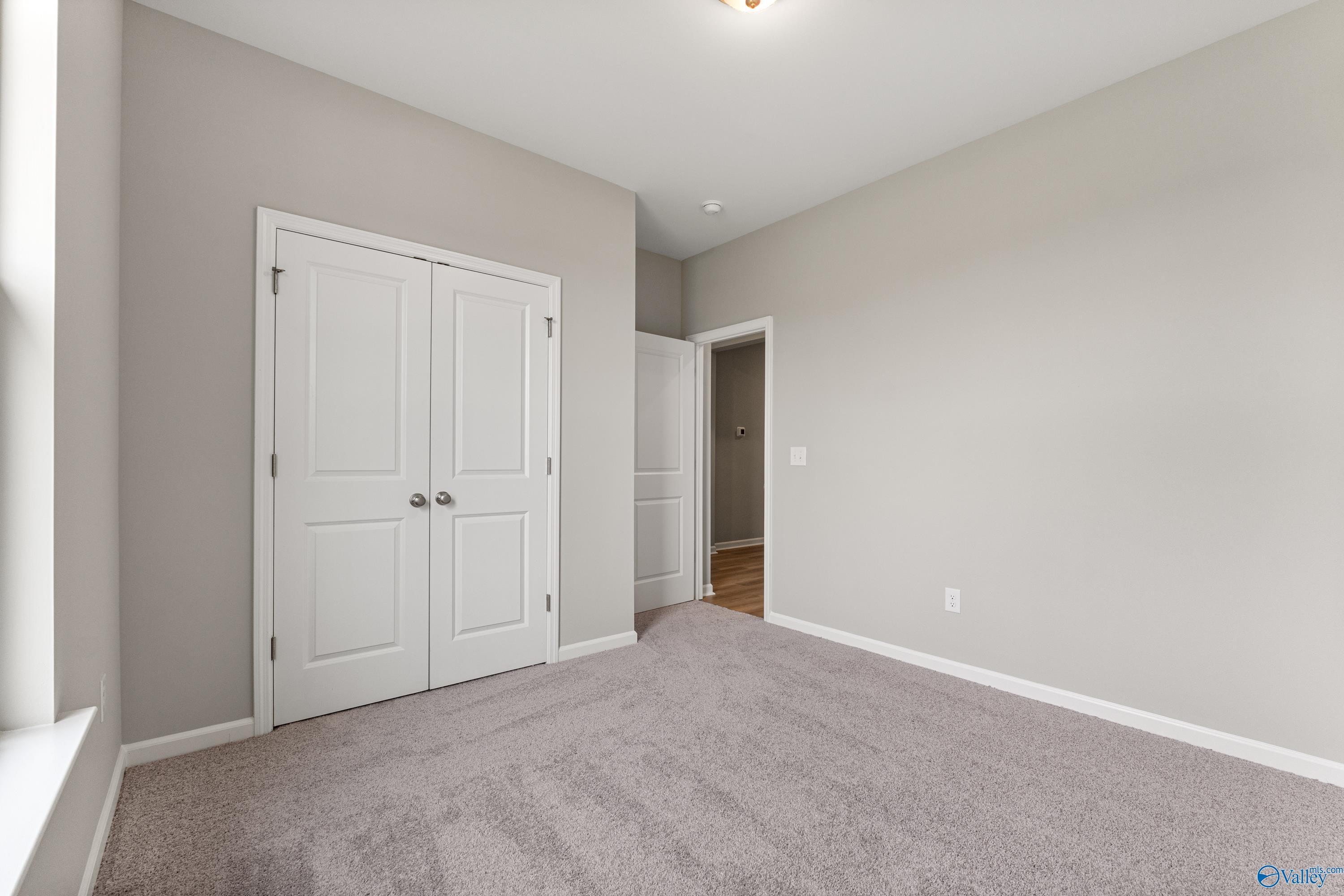 Neutral bedroom with light gray walls, double closet doors, and en-suite entry in Davidson Homes The Aurora, Fayetteville, TN