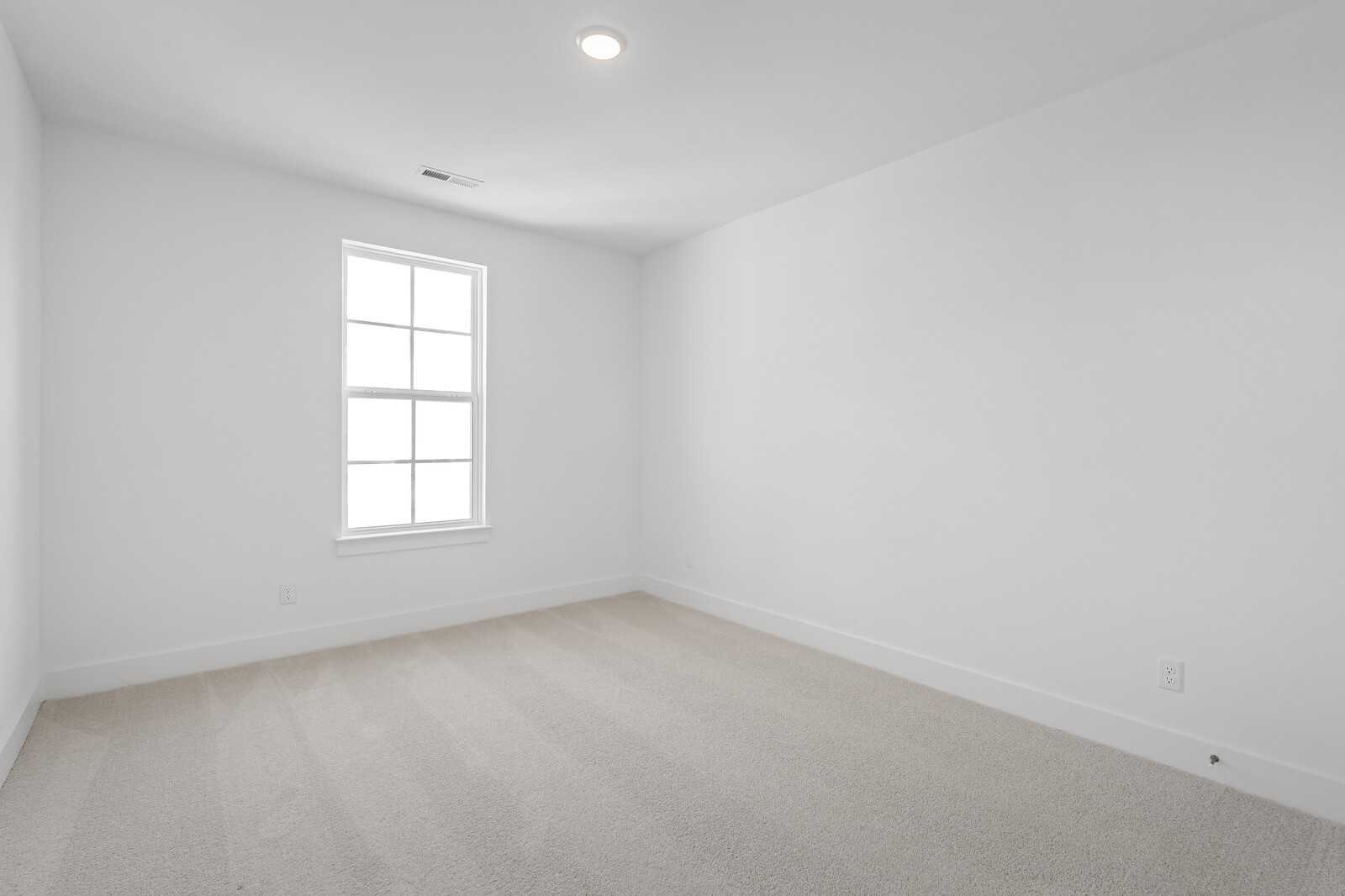 Empty bedroom featuring white walls, large window, beige carpet in 4-bedroom The Hawkins home by Davidson Homes, Murfreesboro, TN