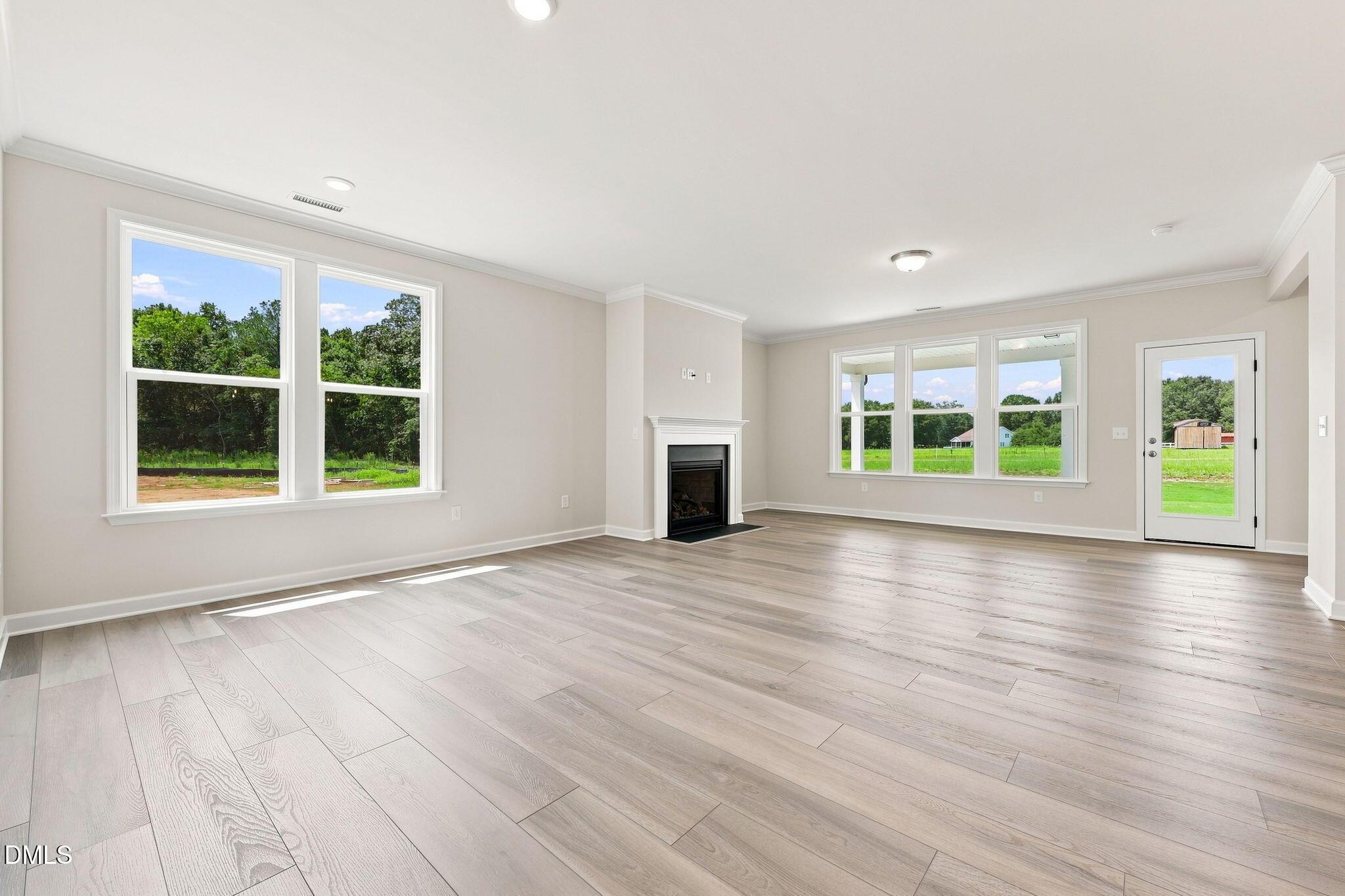 Spacious living room with fireplace and wood-look flooring in The Magnolia B floor plan at Retreat at North Main, Lillington.