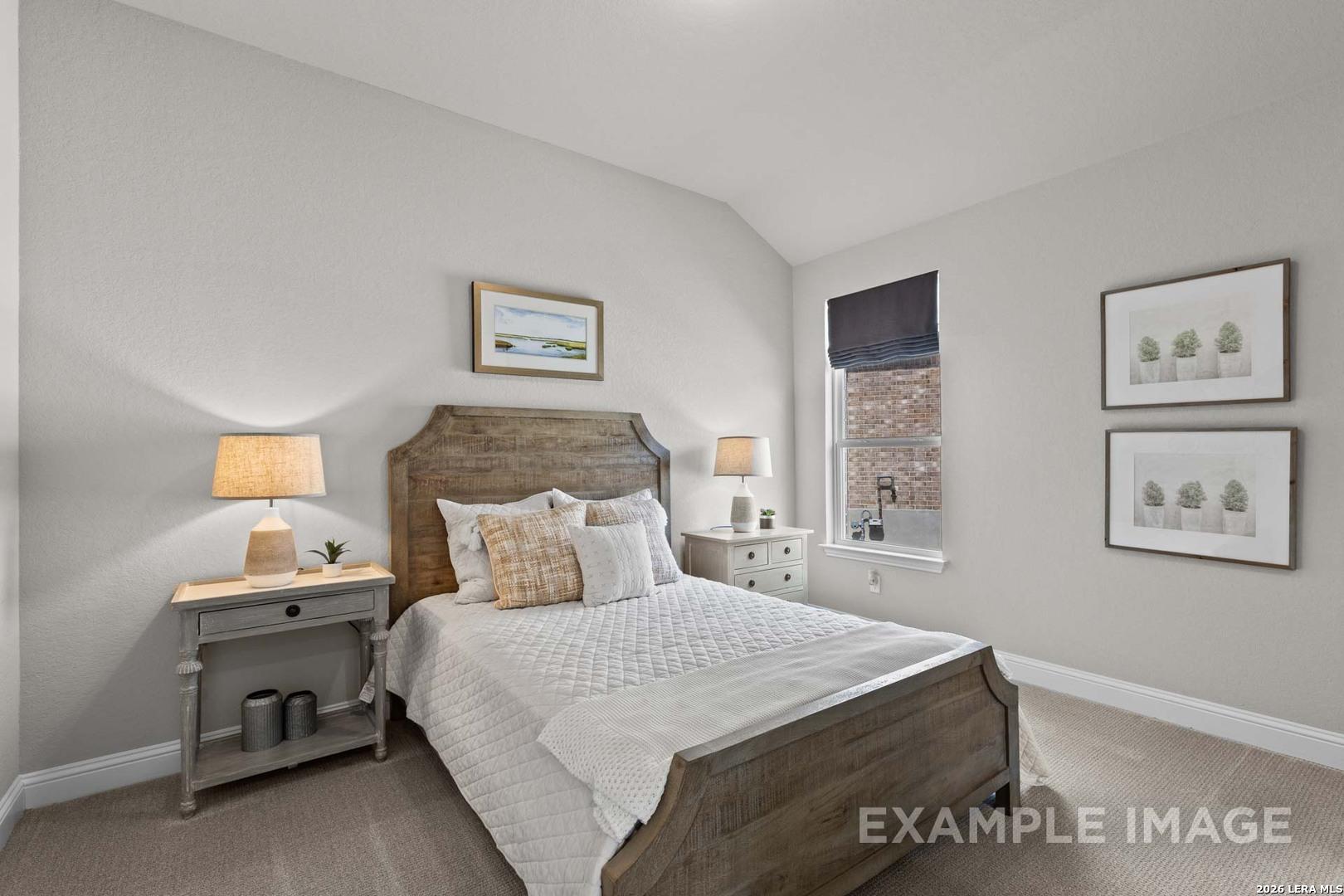 Cozy guest bedroom with rustic wooden bed frame in The Garner C floor plan at The Reserve at Potranco Oaks, Castroville, TX.
