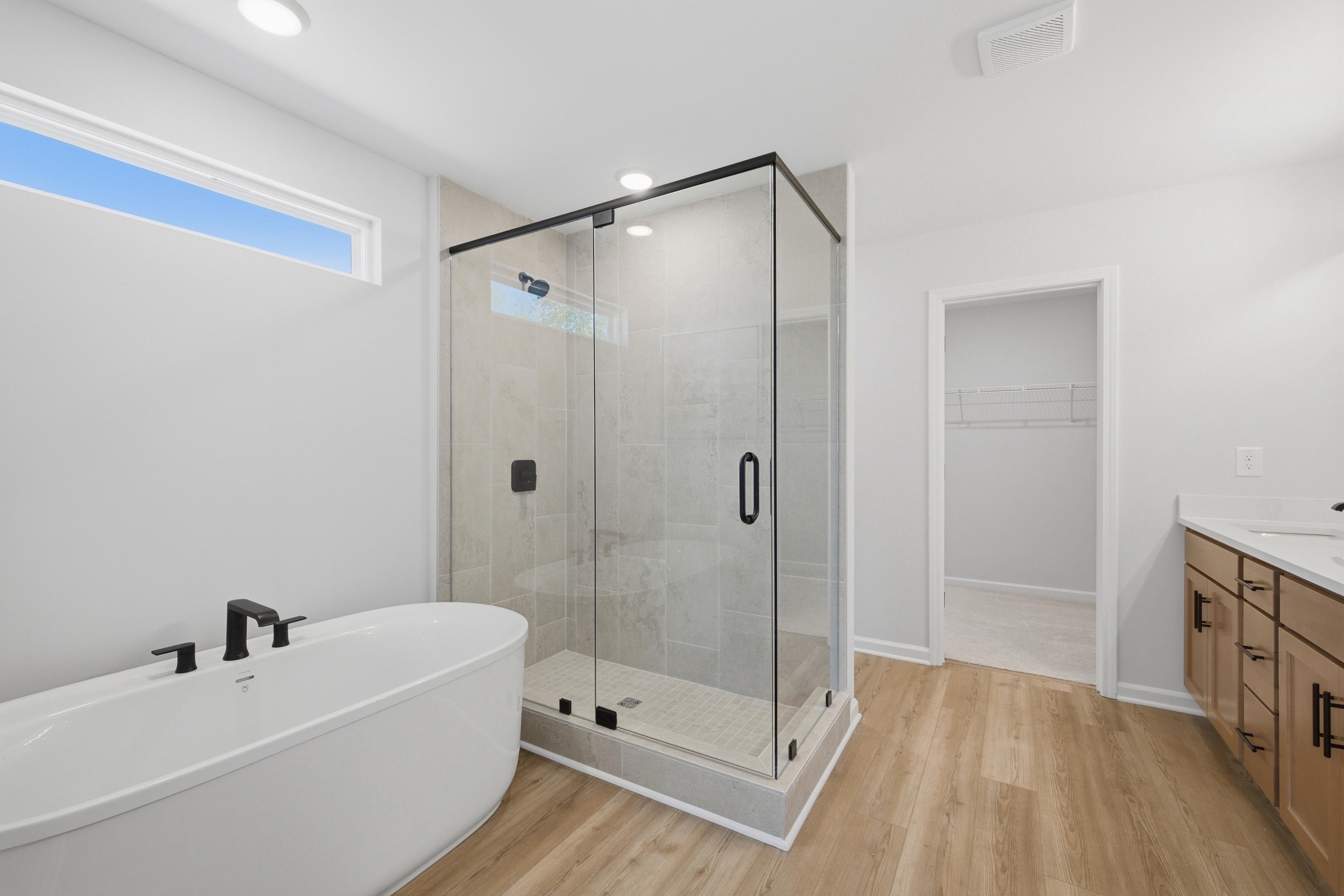 Owner's bathroom at Greene Farm by Davidson Homes in Cartersville, GA with freestanding tub, glass shower, and wood-look floors