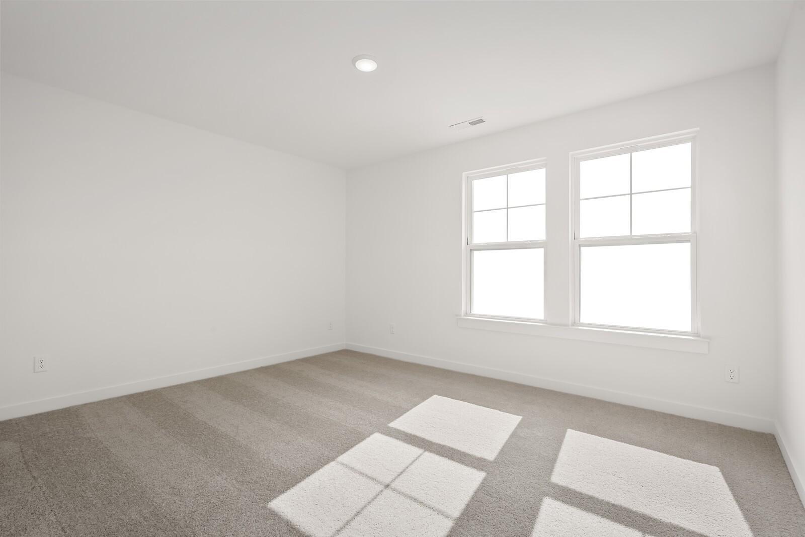 Bright secondary bedroom with white walls, double windows, and gray carpet in The Logan C by Davidson Homes, Gallatin, TN