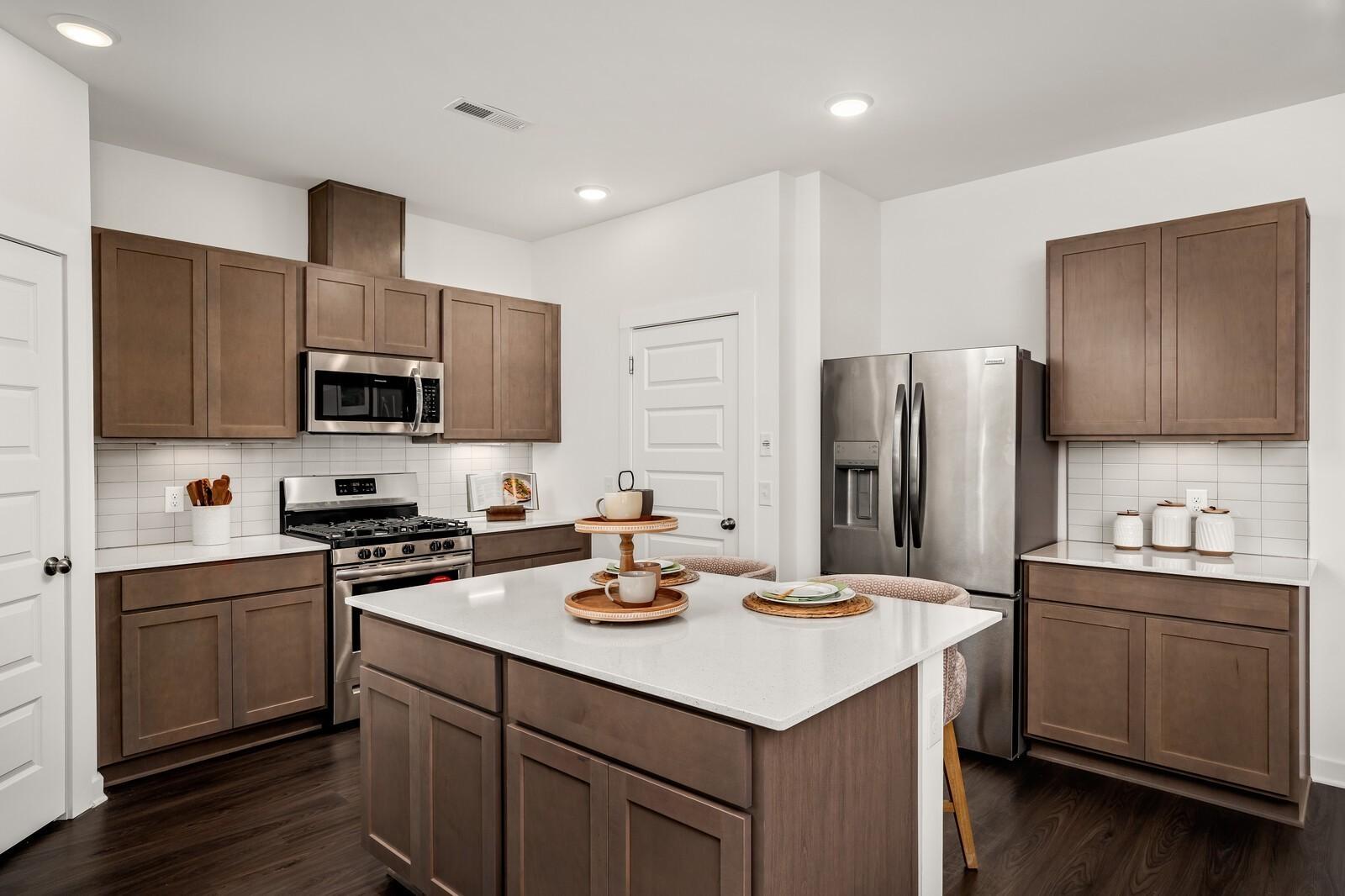 Modern shaker kitchen with white quartz island, stainless steel appliances, subway tile backsplash in Davidson Homes The Gordon C, White House, TN