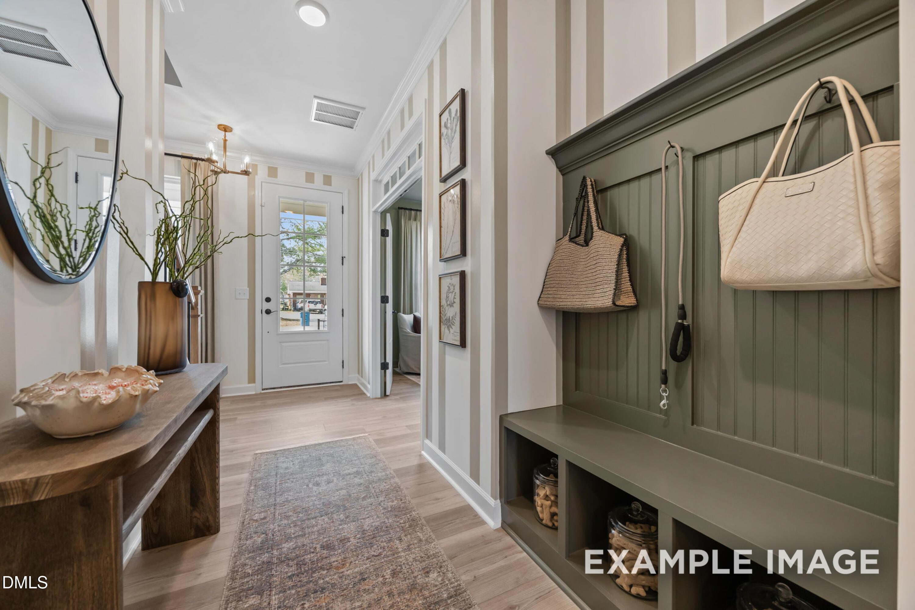 Welcoming foyer with mudroom bench, sage shiplap storage, and glass-panel front door in Davidson Homes Avery plan, Knightdale NC