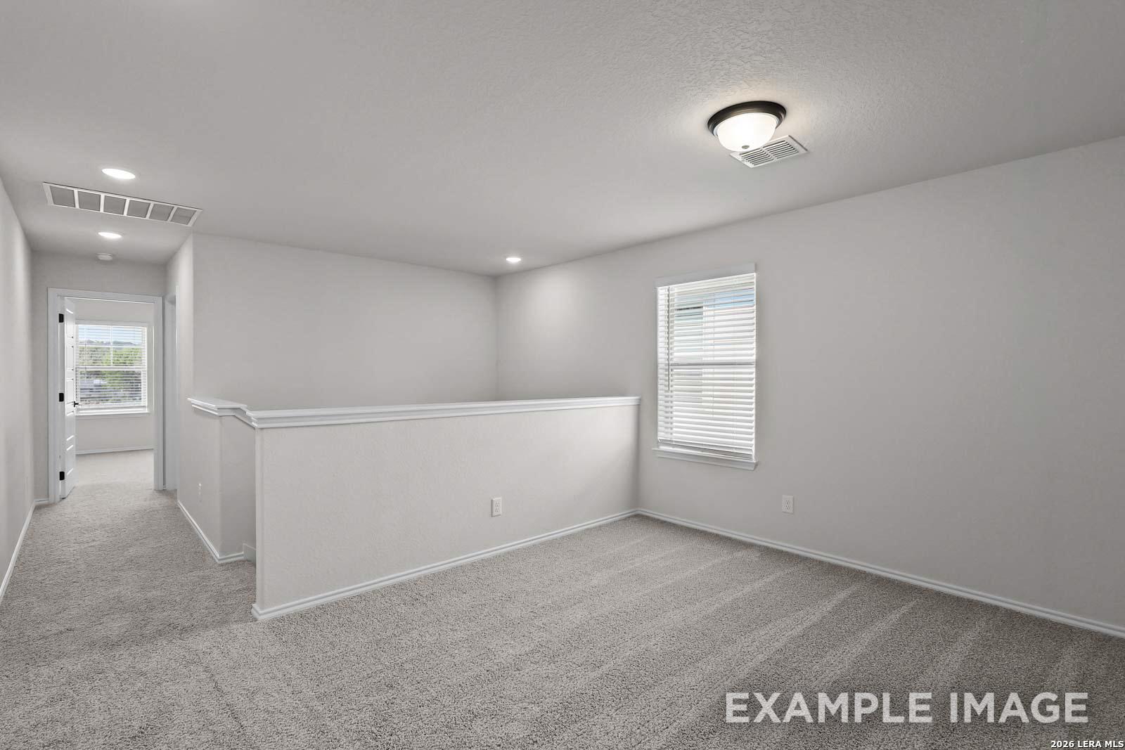 Spacious upstairs loft area with neutral carpet in The Florence D floor plan by Davidson Homes in San Antonio, Texas.