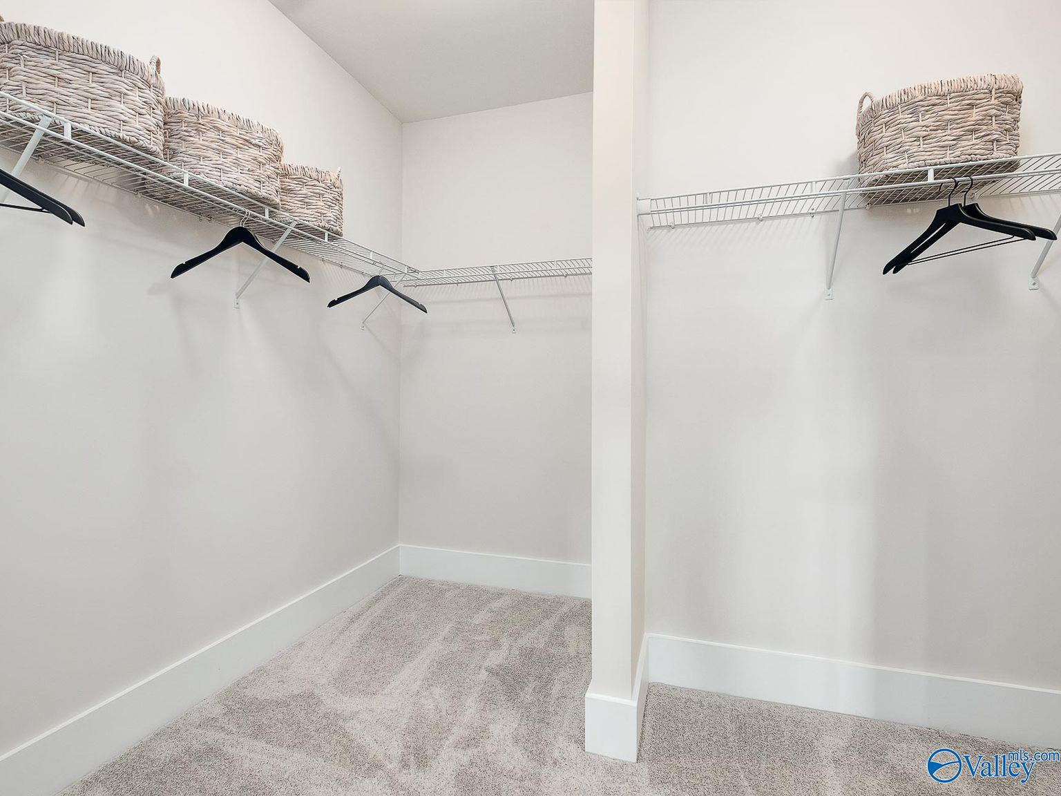 Spacious walk-in closet with wire shelving, hanging rods, and wicker baskets in The Everett master suite by Davidson Homes, Toney, Alabama