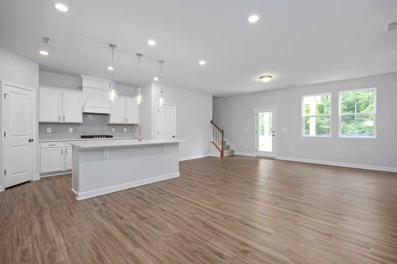 Modern open-concept kitchen with white shaker cabinets, quartz island, and hardwood floors in The Durham D home, Wylie, Texas