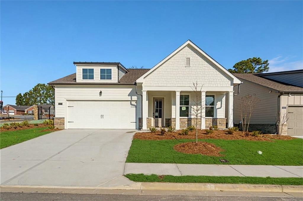 Modern white shake siding 1-story home with 2-car garage, covered porch, and landscaped front yard in Kelly Preserve, Loganville, Georgia