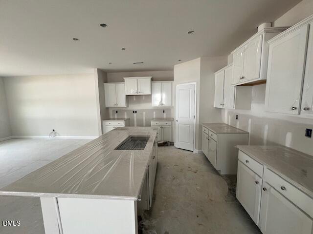 Modern open-concept kitchen with white shaker cabinets, large island, and granite counters in The Preston A by Davidson Homes, Lillington, NC