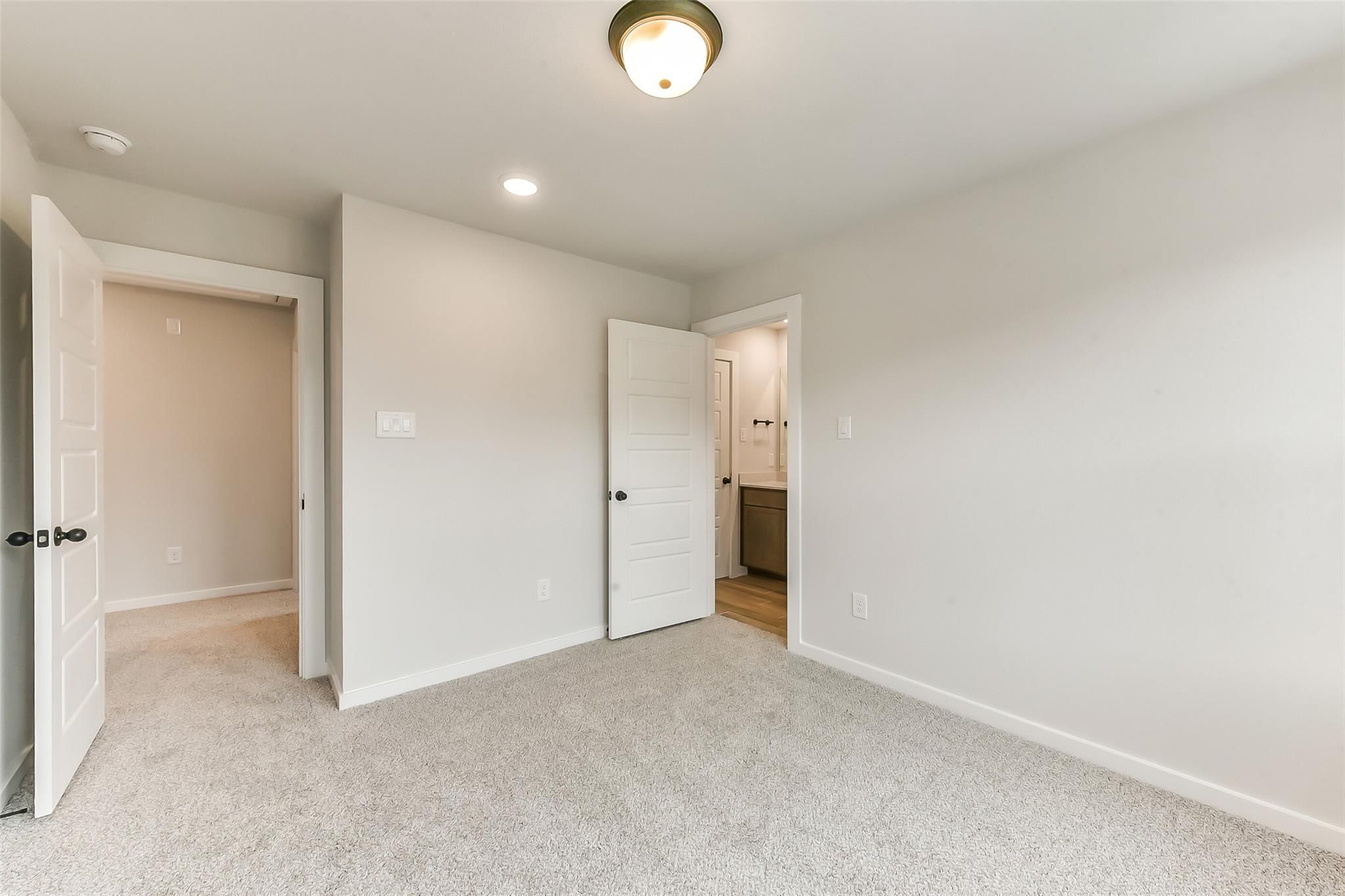 Spacious secondary bedroom with attached bath, plush beige carpet, and soft gray walls in Davidson Homes The Sequoia C, Crosby, Texas