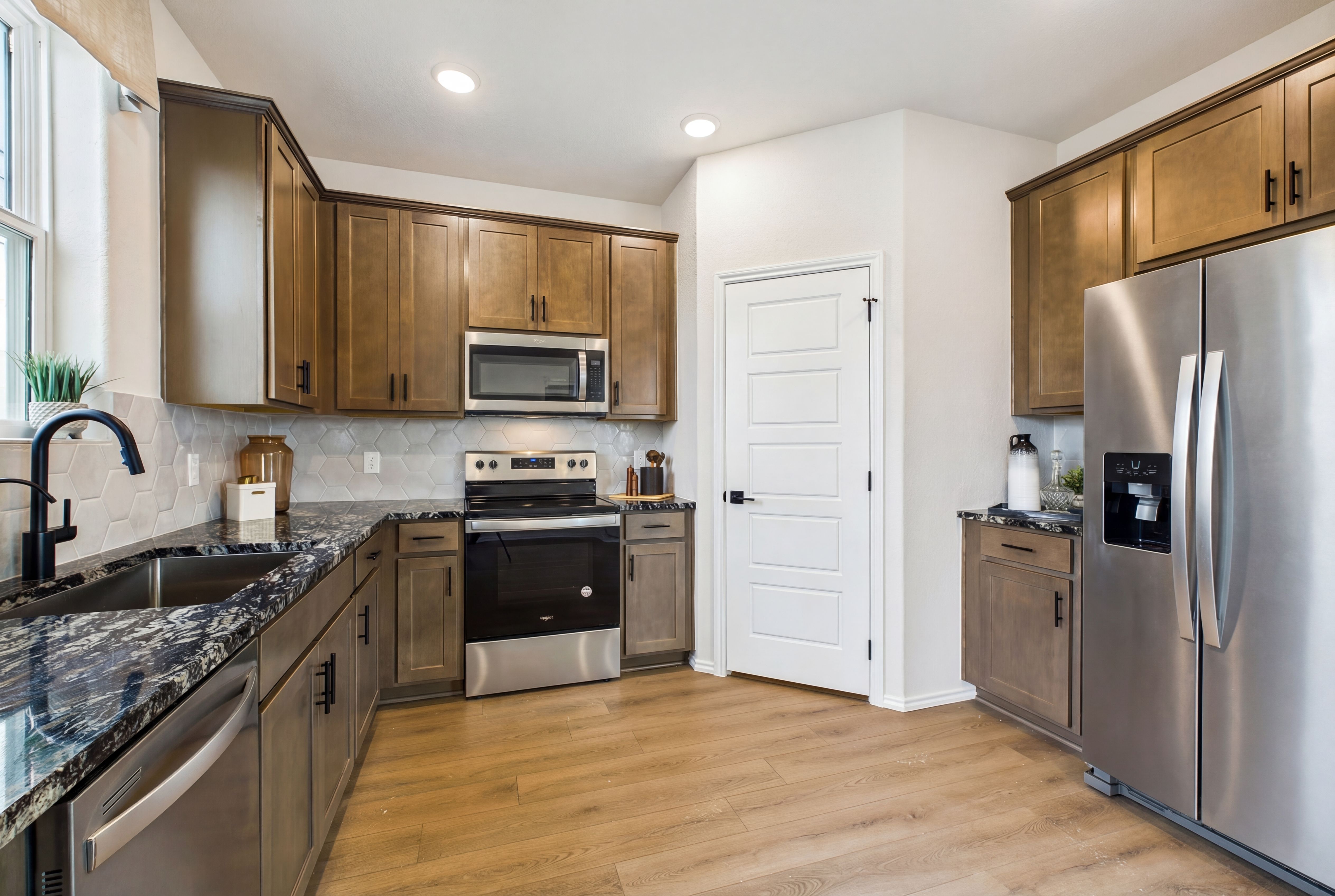 Modern shaker kitchen in Meadows at Oak Creek San Antonio TX with granite counters stainless appliances and hardwood floors