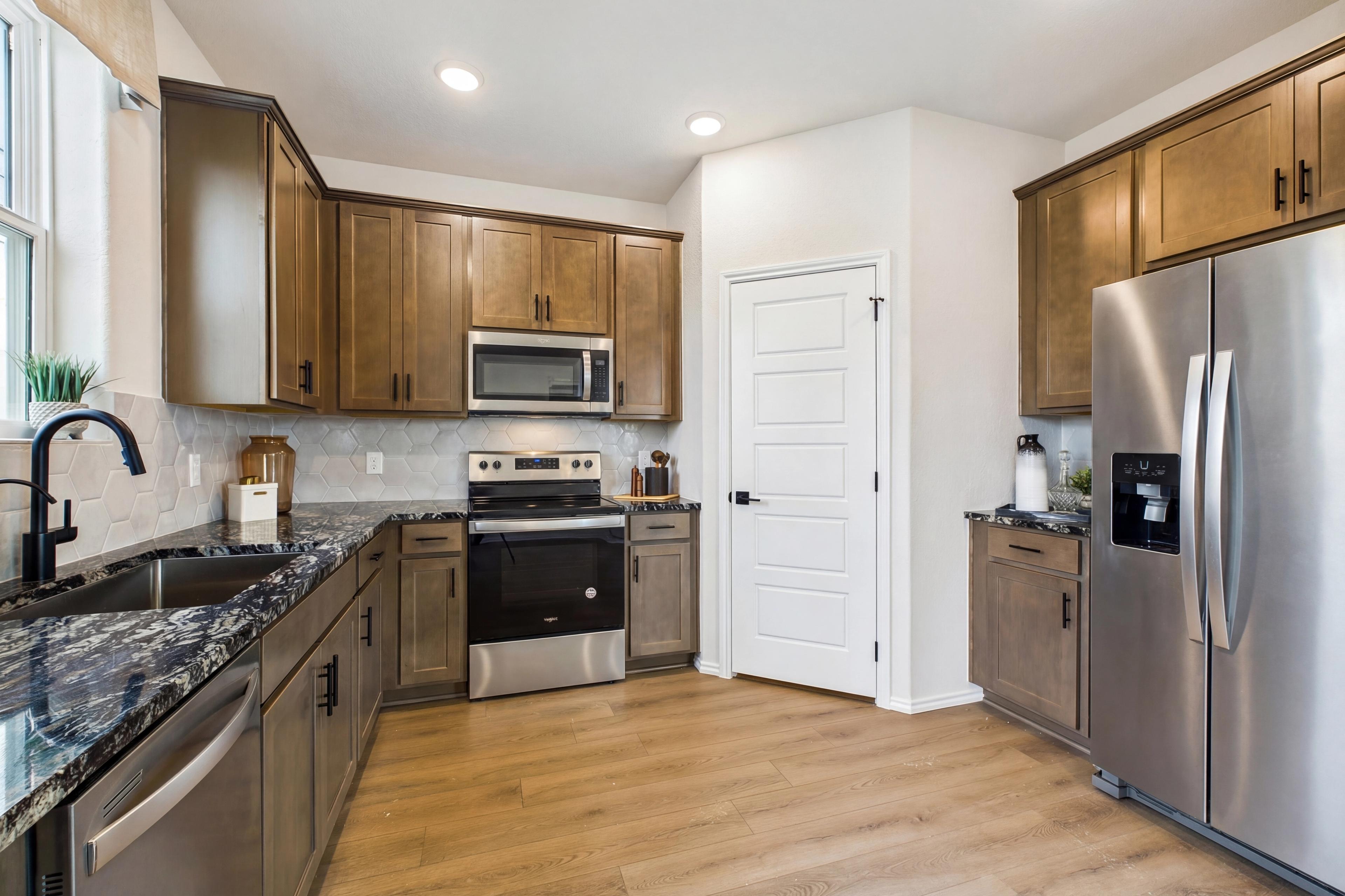Modern shaker kitchen in Meadows at Oak Creek San Antonio TX with granite counters stainless appliances and hardwood floors