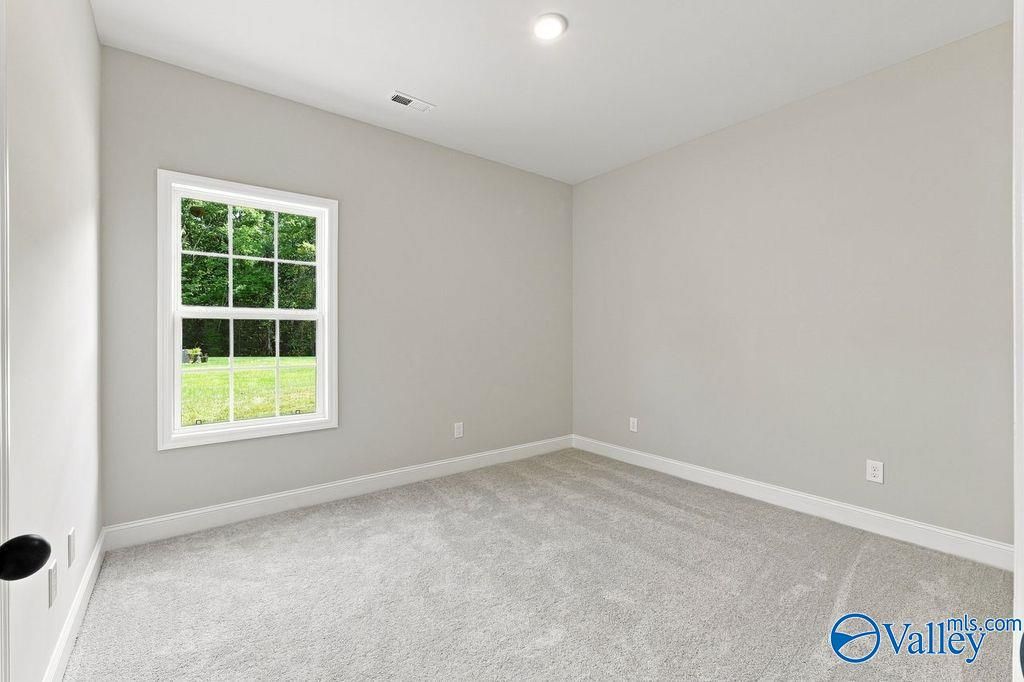 Bright bedroom with new carpet and white-trimmed window overlooking backyard in Davidson Homes Rockford plan, Hartselle, AL