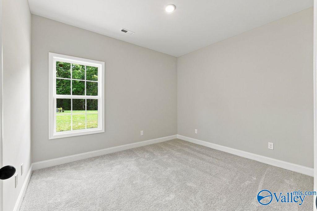 Bright bedroom with new carpet and white-trimmed window overlooking backyard in Davidson Homes Rockford plan, Hartselle, AL