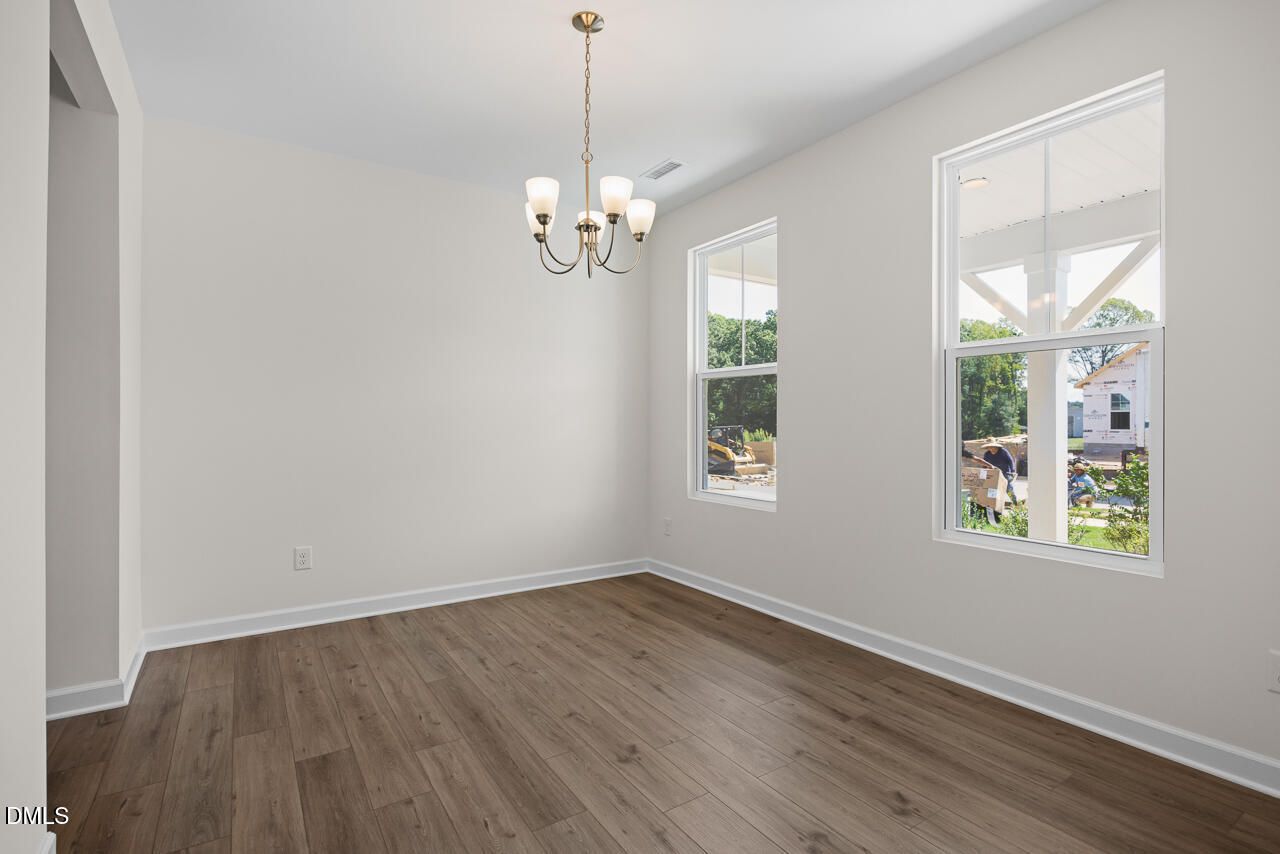 Bright dining room with luxury vinyl plank flooring, chandelier, and large windows in Davidson Homes The Willow B, Zebulon NC