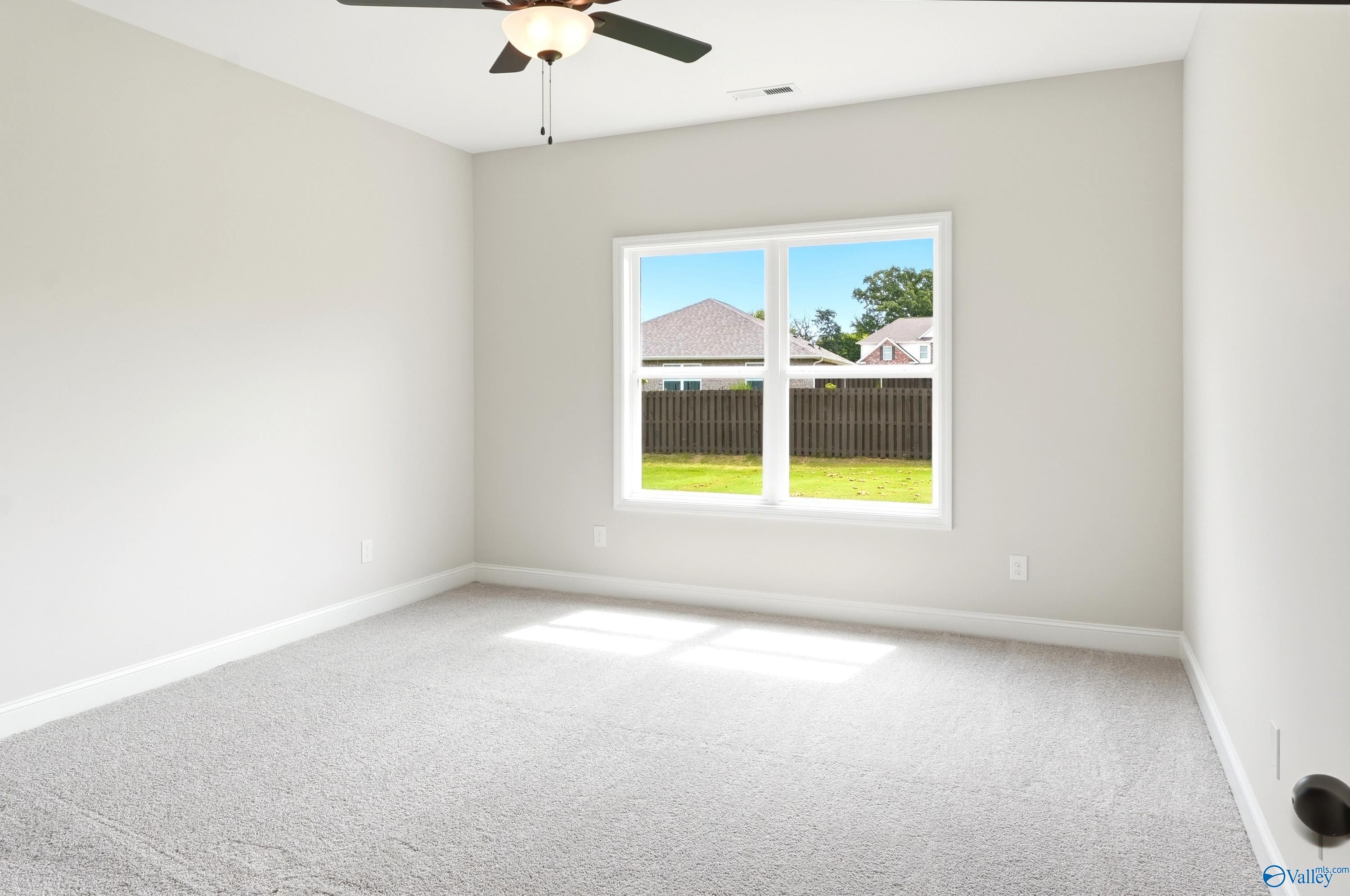 Bright, carpeted bedroom with ceiling fan in The Daphne C floor plan at Flint Meadows, New Market, Alabama.