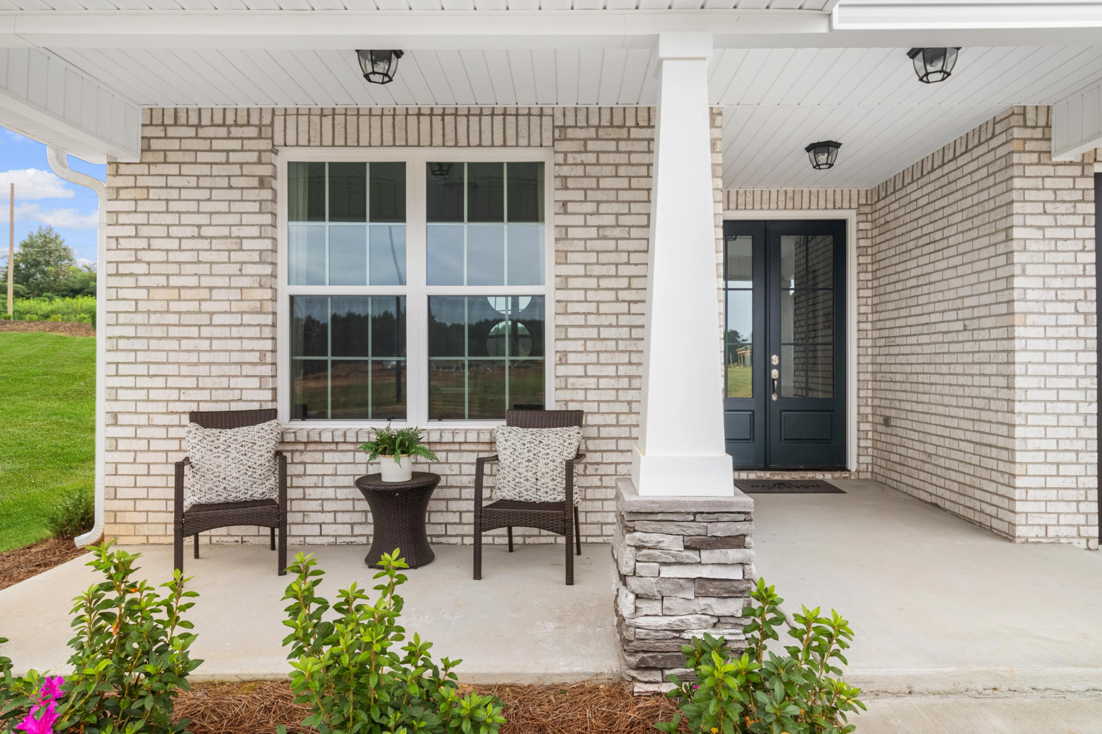 Brick home exterior with covered porch, wicker seating and plants at North Ridge in Cullman, Alabama by Davidson Homes