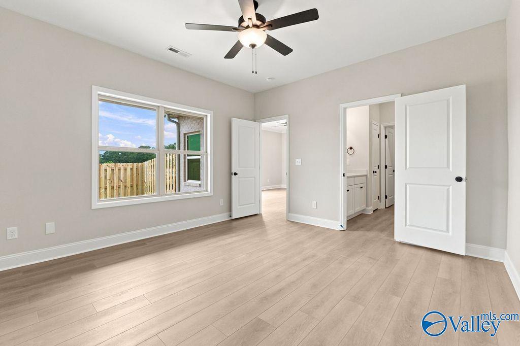Bright bedroom with wood-look flooring and ceiling fan in The Camilla B floor plan at The Retreat at Cain Park, Hartselle.