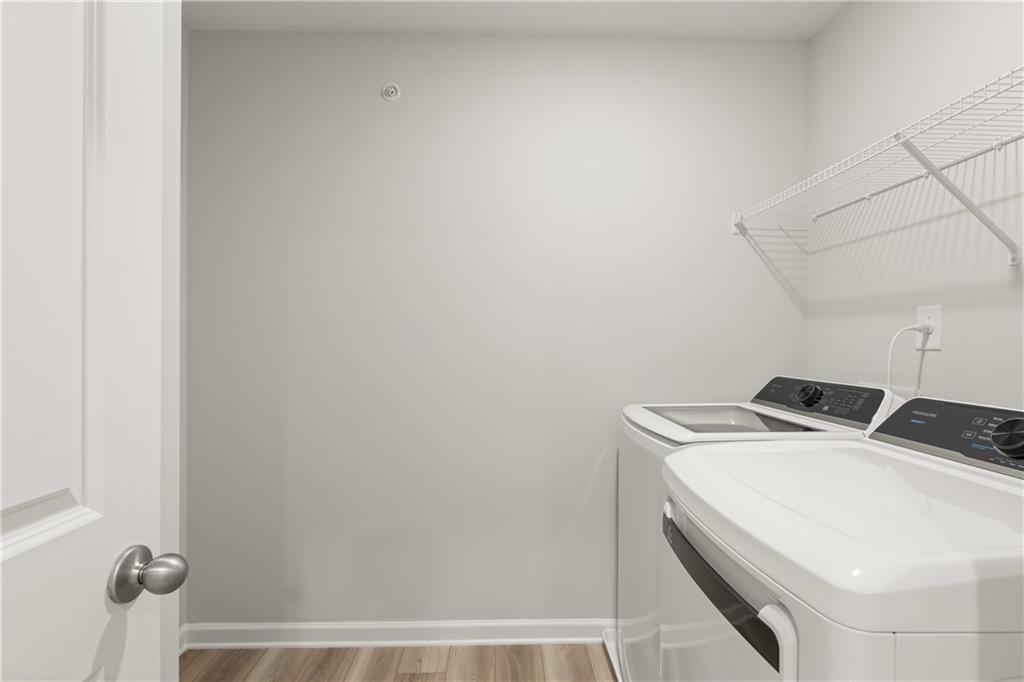 Laundry room with white washer and dryer and wire shelving in The Wake G floor plan at Hemingway in Cumming, Georgia.